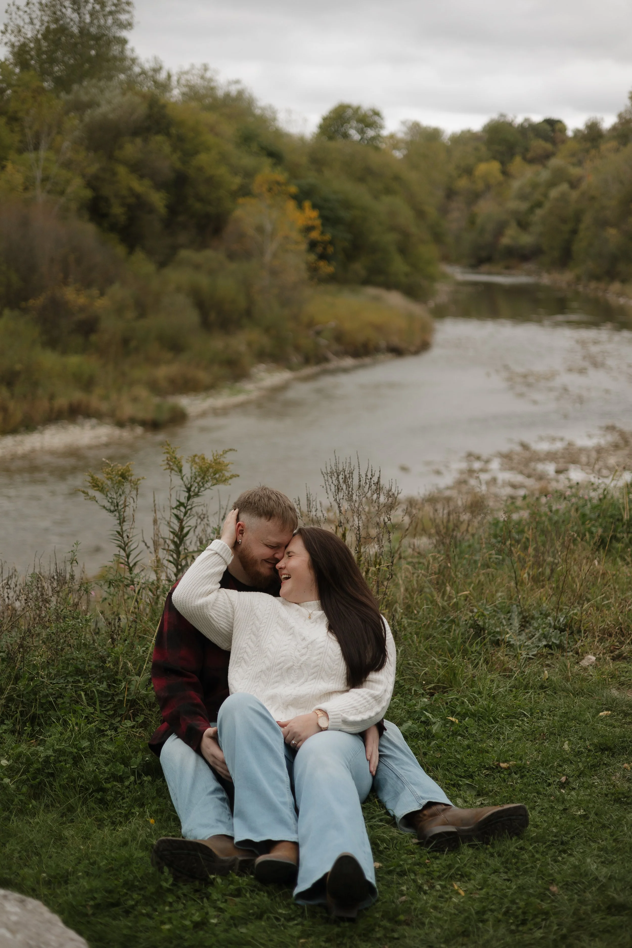 Engaged couple romantically cuddling above the grand river in Paris Ontario