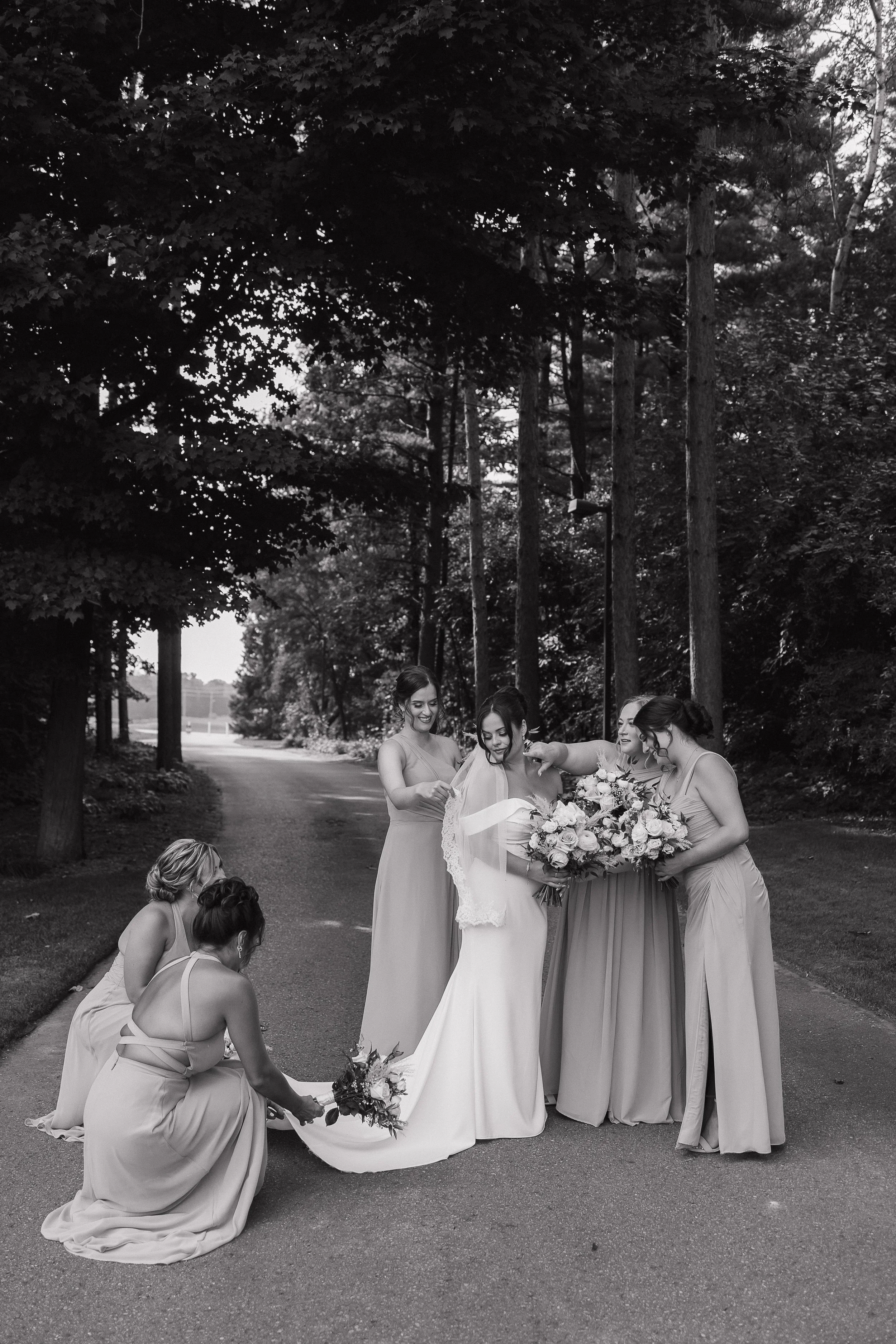 Bridesmaids doting on the bride while getting her ready for the ceremony in Ontario, photographed by James and Alyson Photo