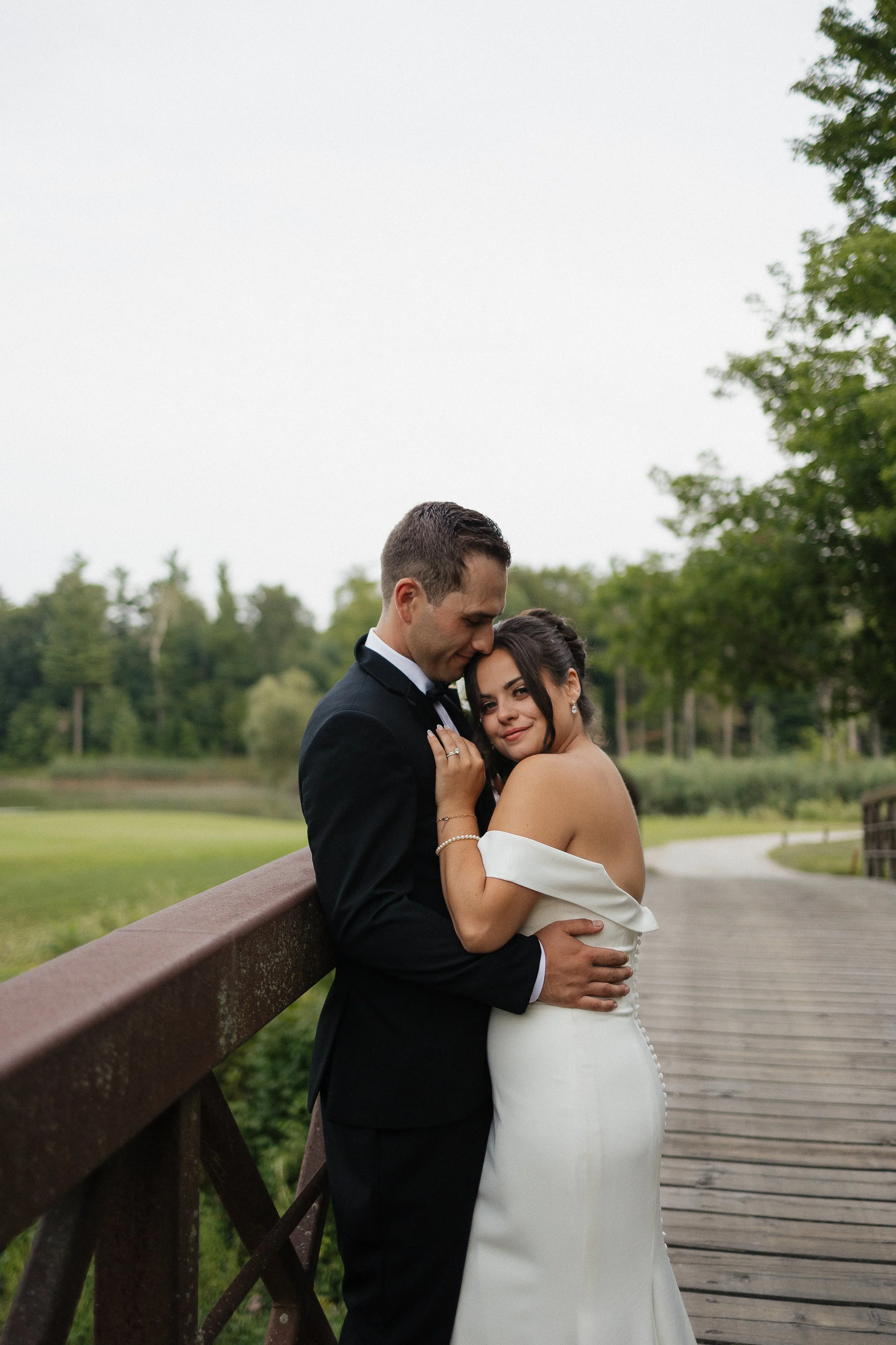bride and groom hugging on a bridge, Ontario wedding photography by James and Alyson Photography