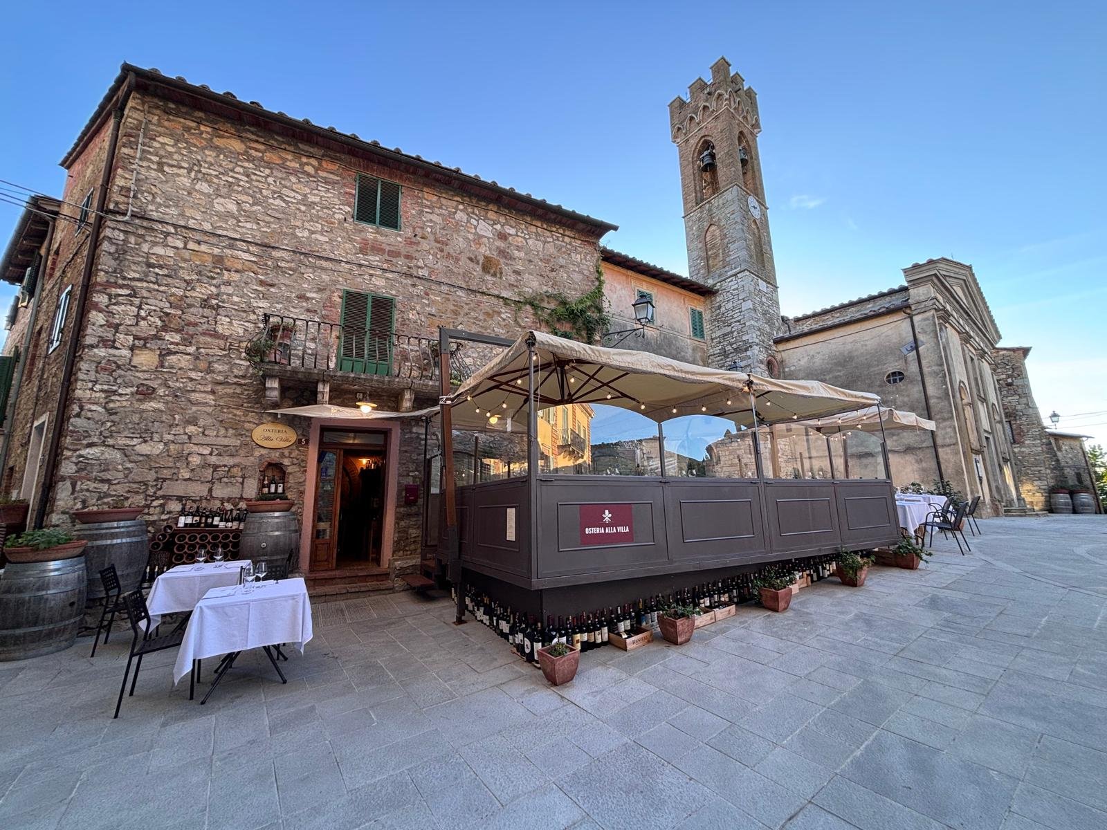 Outdoor seating of a rustic Italian restaurant in a picturesque small village piazza. This unique restaurant is the best restaurant for wine lovers and foodie enthusiasts. Siena, Castelnuovo Berardenga, Villa A Sesta Restaurant.
