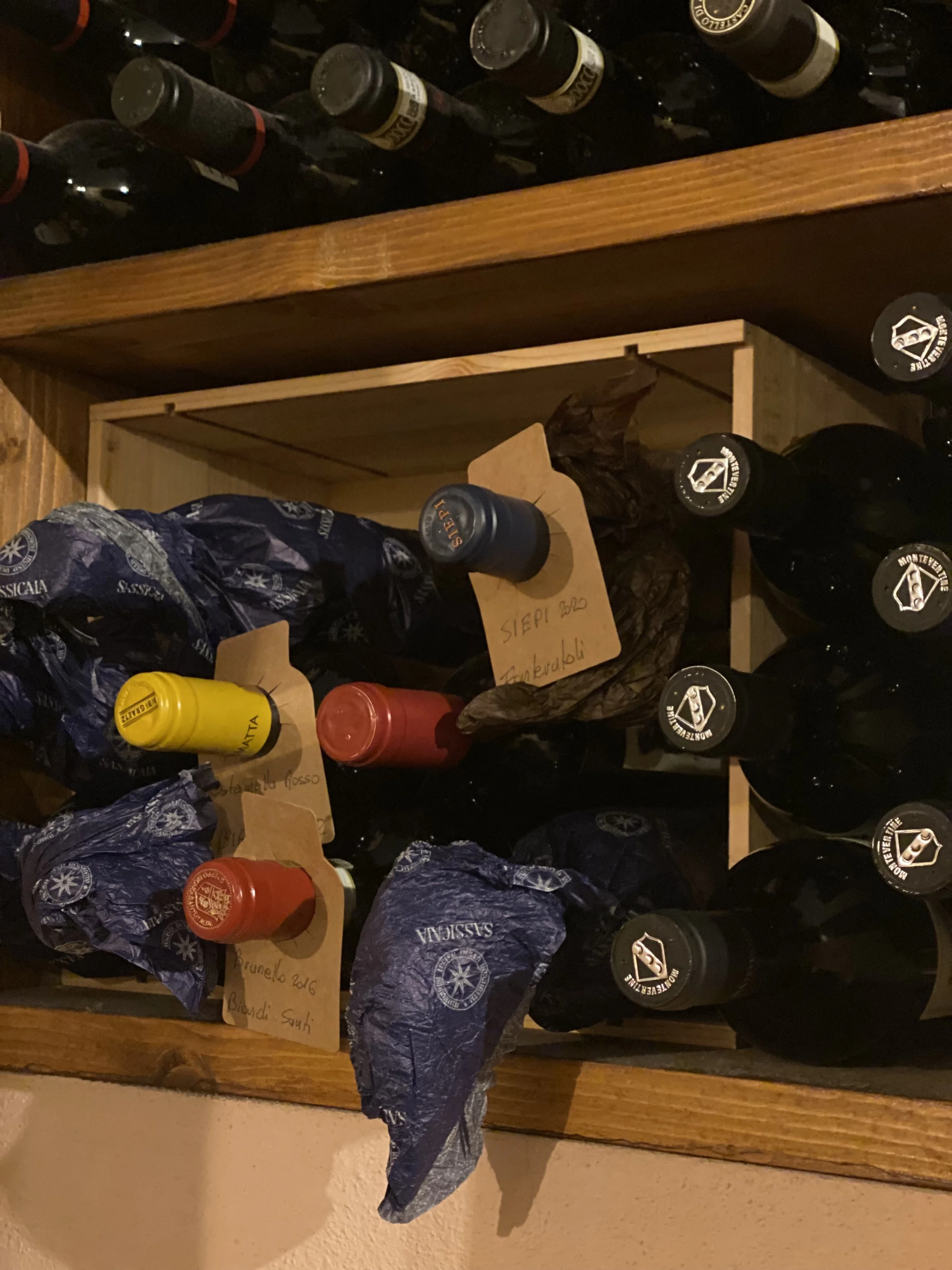 A wooden wine rack holding several bottles of Sassicaia wine available with your meal at Osteria Alla Villa. Sommelier-owned restaurant as an extensive premium wine list and enoteca.
