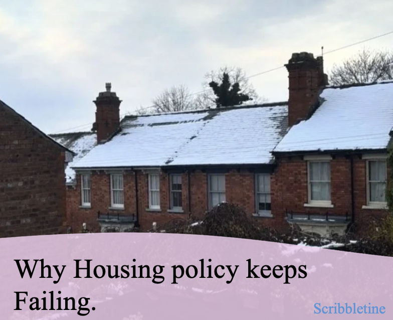 A brick house with a snow-covered roof and chimney, alongside other similar houses, under a cloudy sky.