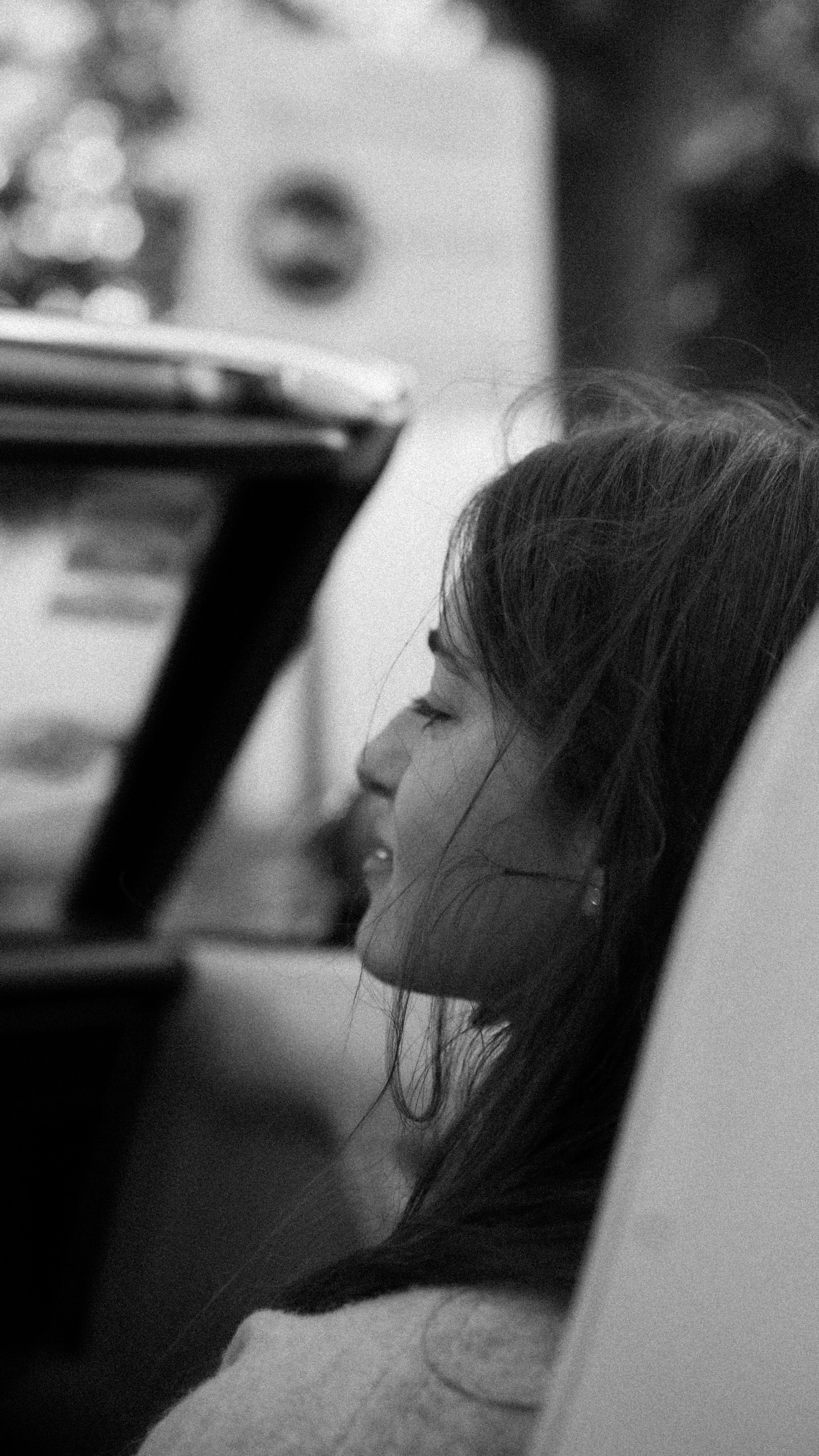 Une jeune femme endormie avec la tête inclinée contre un coussin, vue de profil, en noir et blanc.