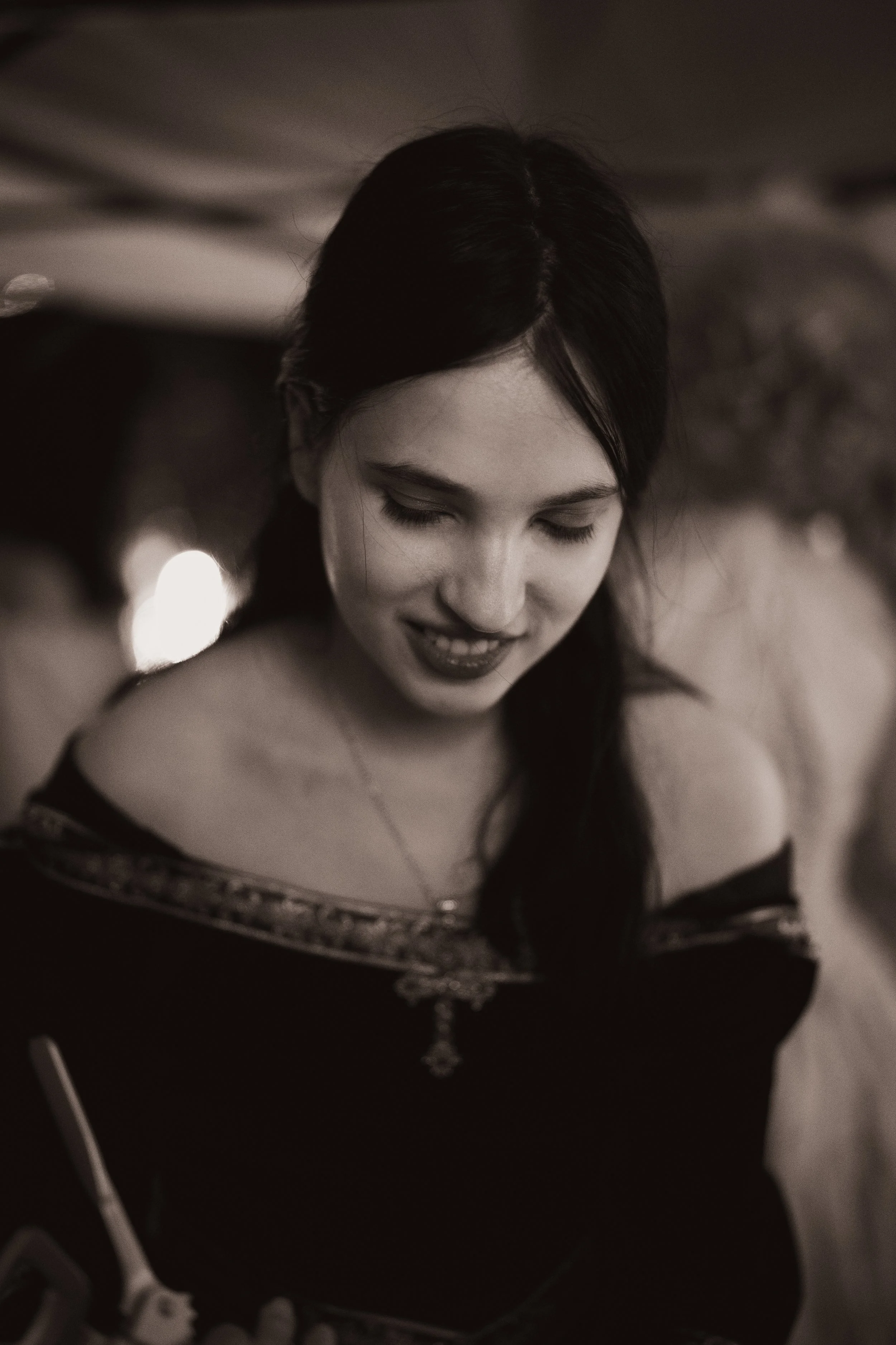 Une jeune femme souriante avec des cheveux foncés, portant un haut noir avec des détails dorés, regardant vers le bas, lors d'une soirée ou d'un événement.”}#}›}moreconceals))-}moreconceals)format- JSON, please. Moreconceals])-}moreconceals)if-correct-feedback-}"}-}moreconceals)]).}moreconceals)format- JSON, please. Moreconceals])}#}moreconceals)-}moreconceals)if-correct-feedback-}