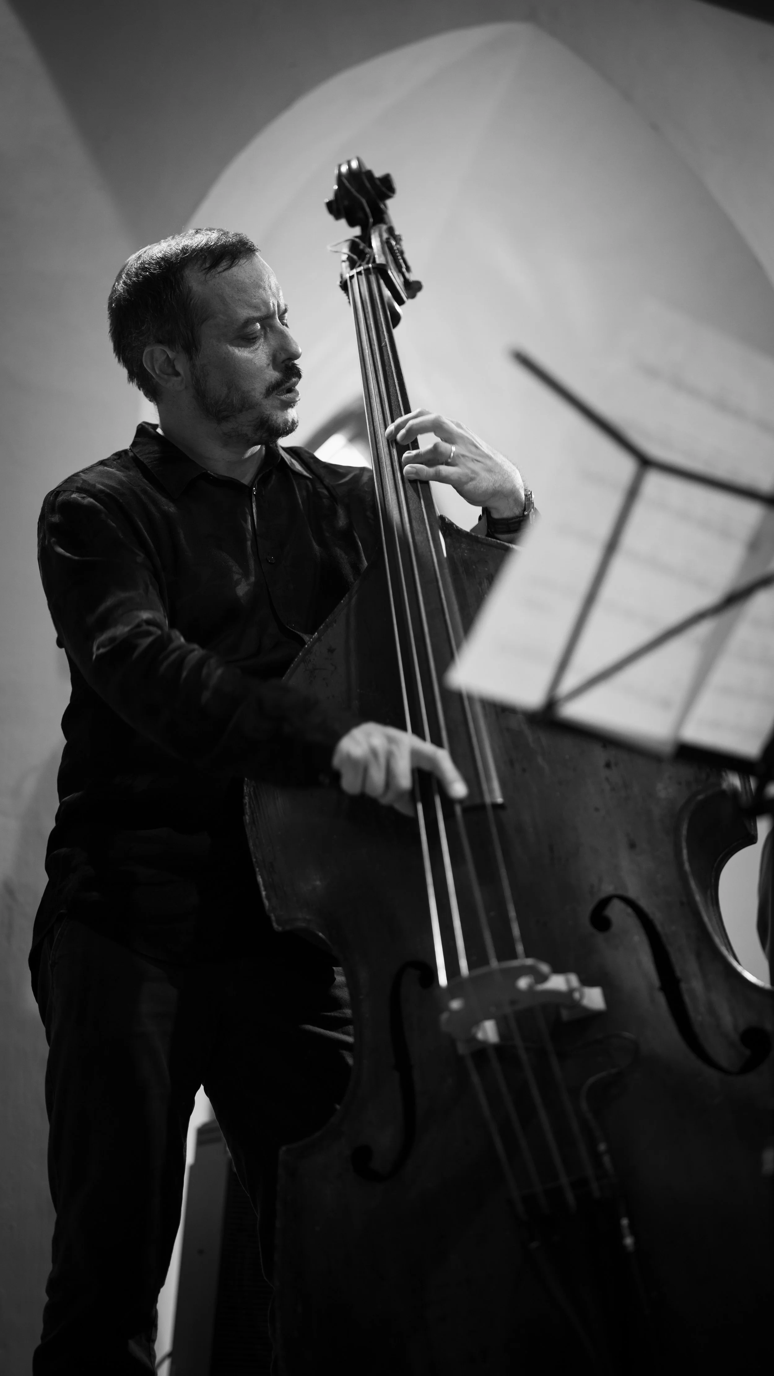 Homme jouant du contrebasse, noir et blanc, intérieur.