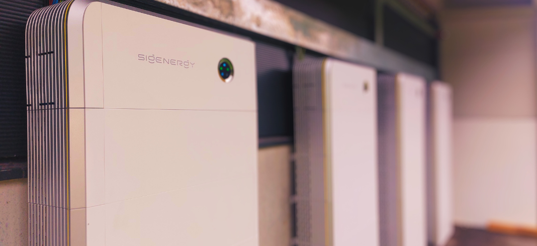 Multiple white power inverters or solar inverter units installed on a wall, with a black shelf above them.