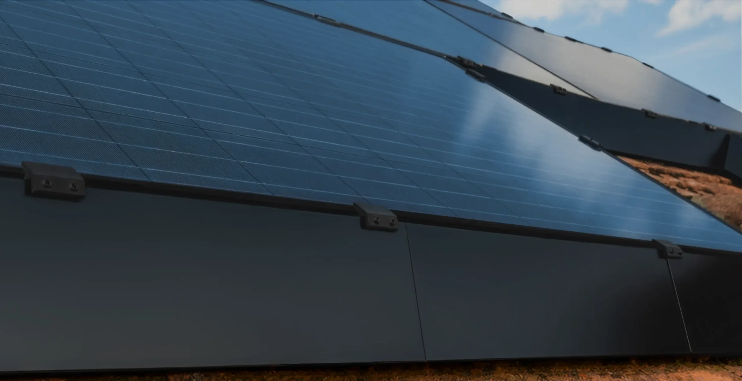 Close-up of solar panels installed on a flat surface under a blue sky with some clouds.