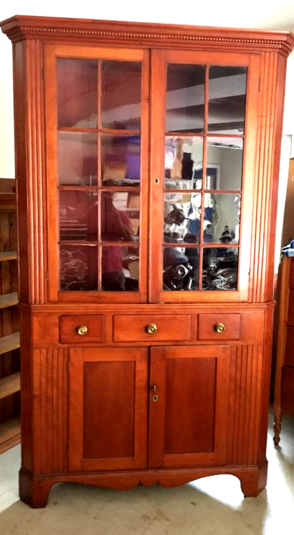 Wooden china cabinet with glass-paneled doors, three small drawers, and two lower doors.