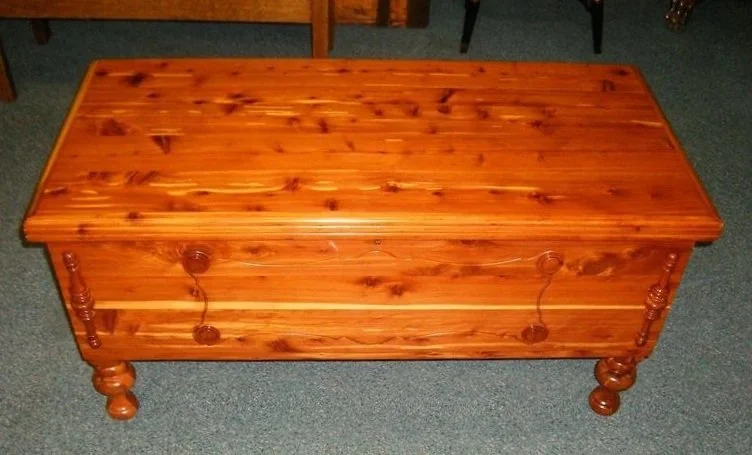 Wooden storage chest or bench with a lid, placed on a carpeted floor.