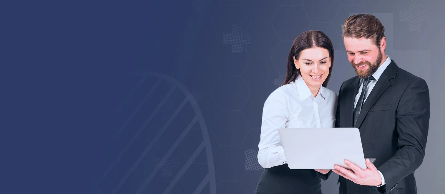 A man and a woman in business attire looking at a laptop, smiling, in a medical or scientific background.