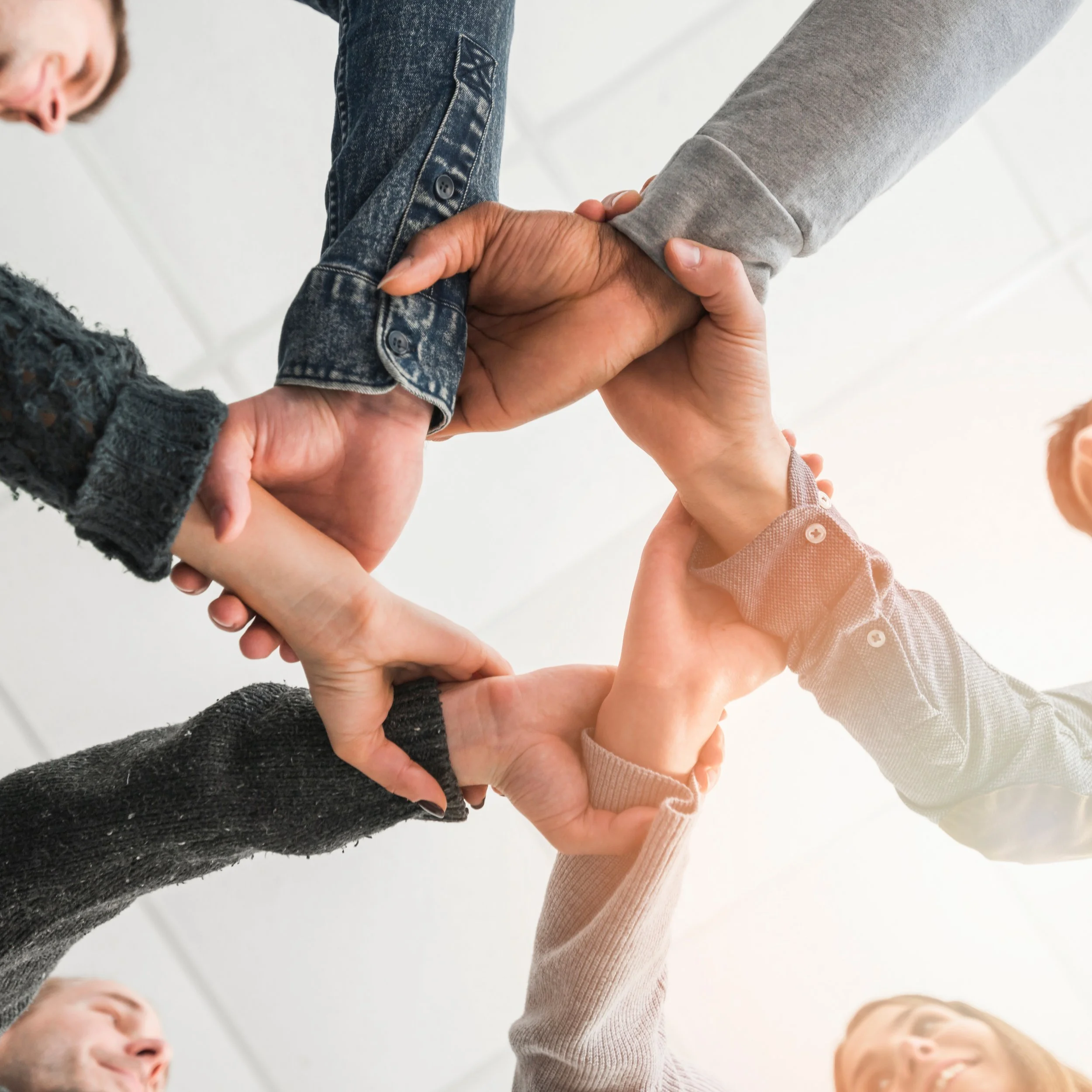 Multiple people making a circle with their hands stacked together in the center.