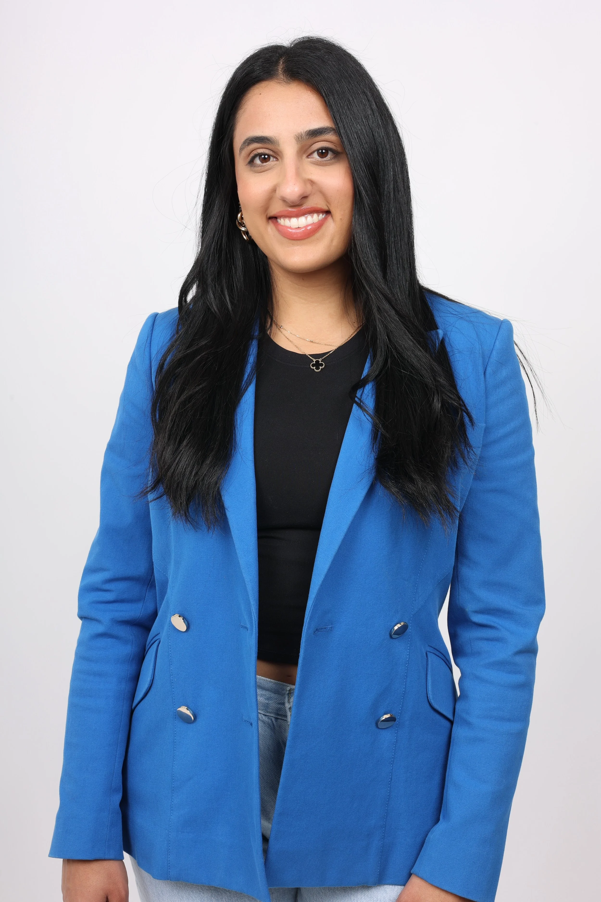Amanda Solomon, wearing a blue blazer over a black top, smiling in front of a plain white background.