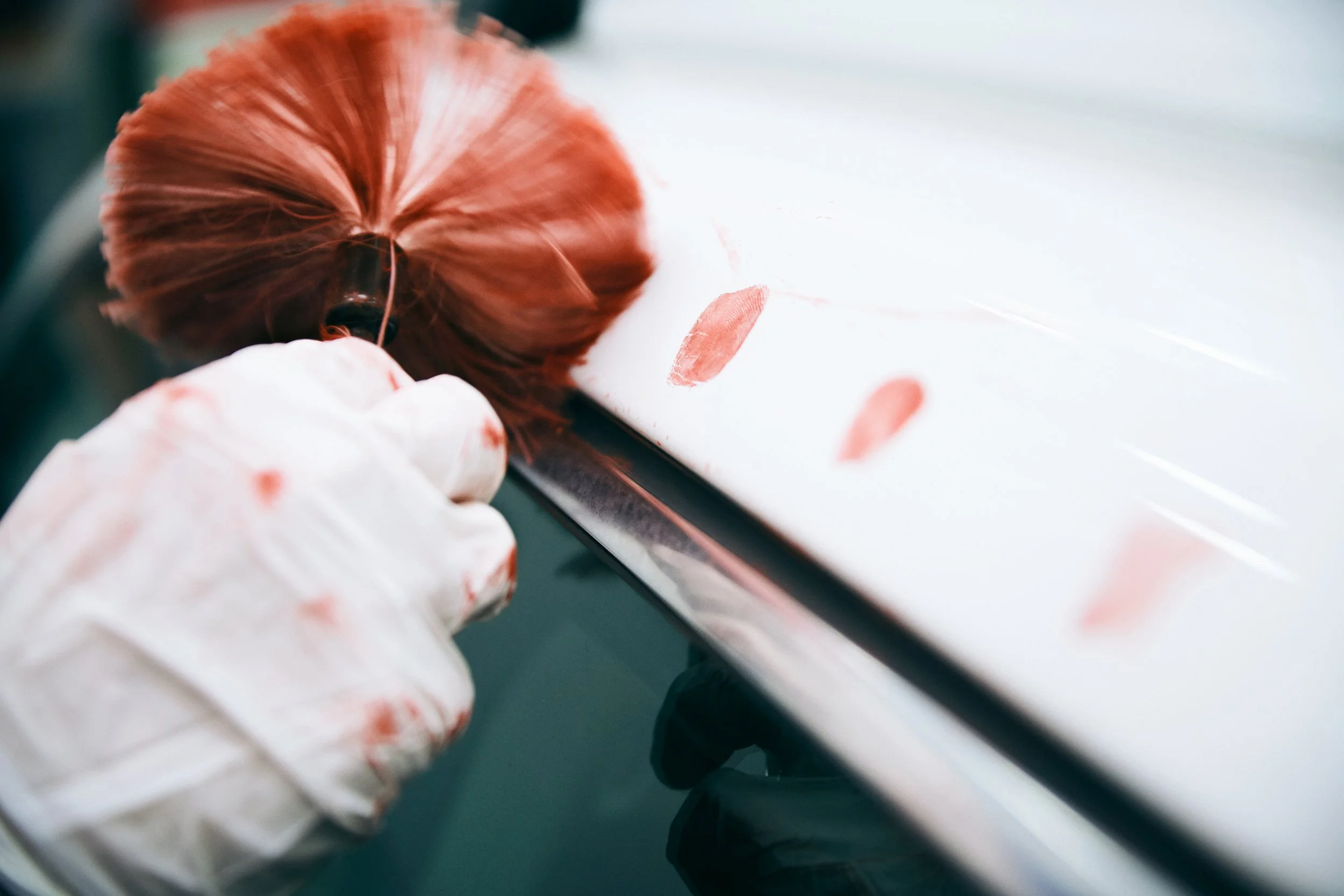 Gloved hand applying powder with brush on car surface