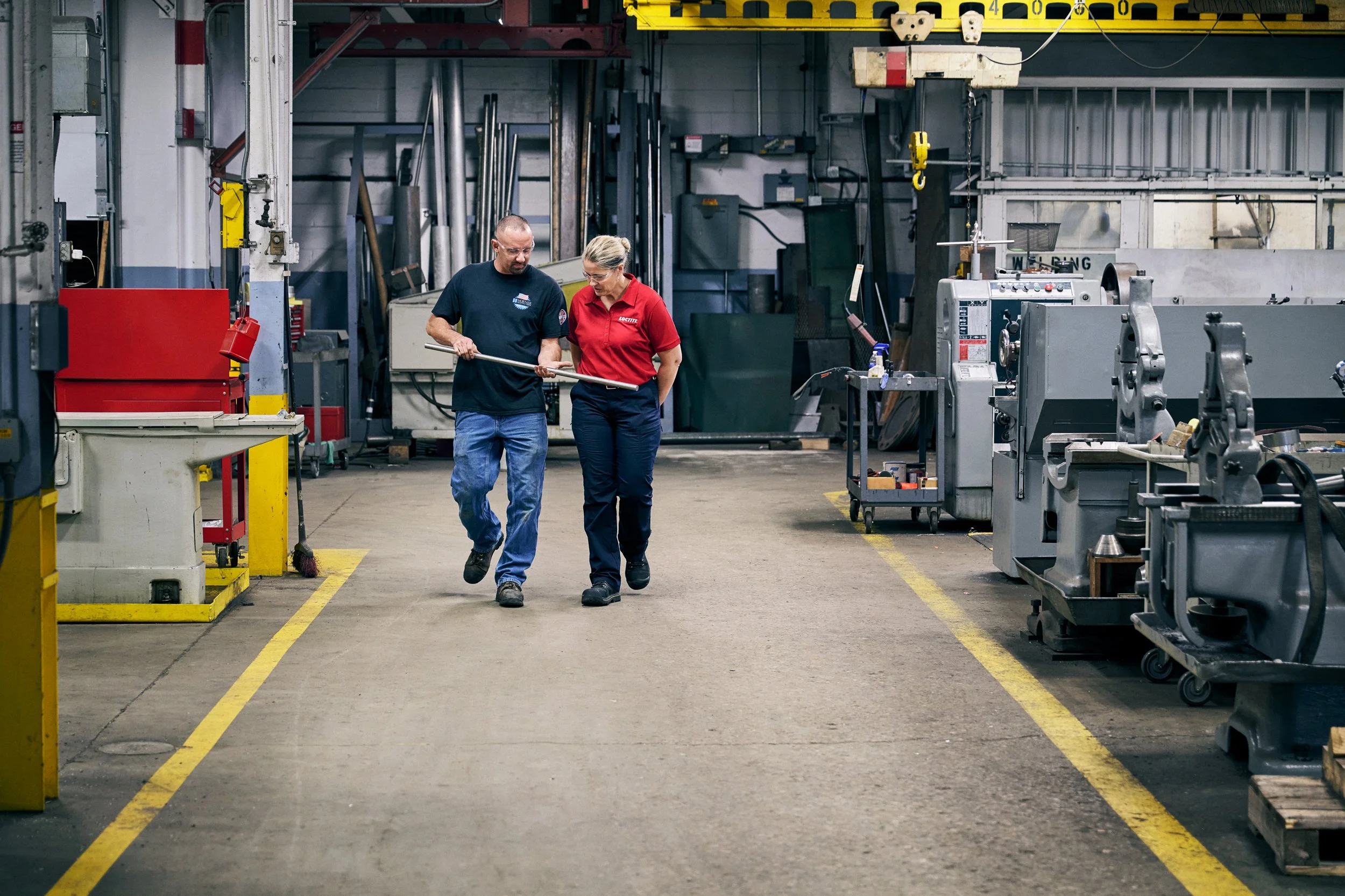 Worker and technician walking through industrial production facility discussing work
