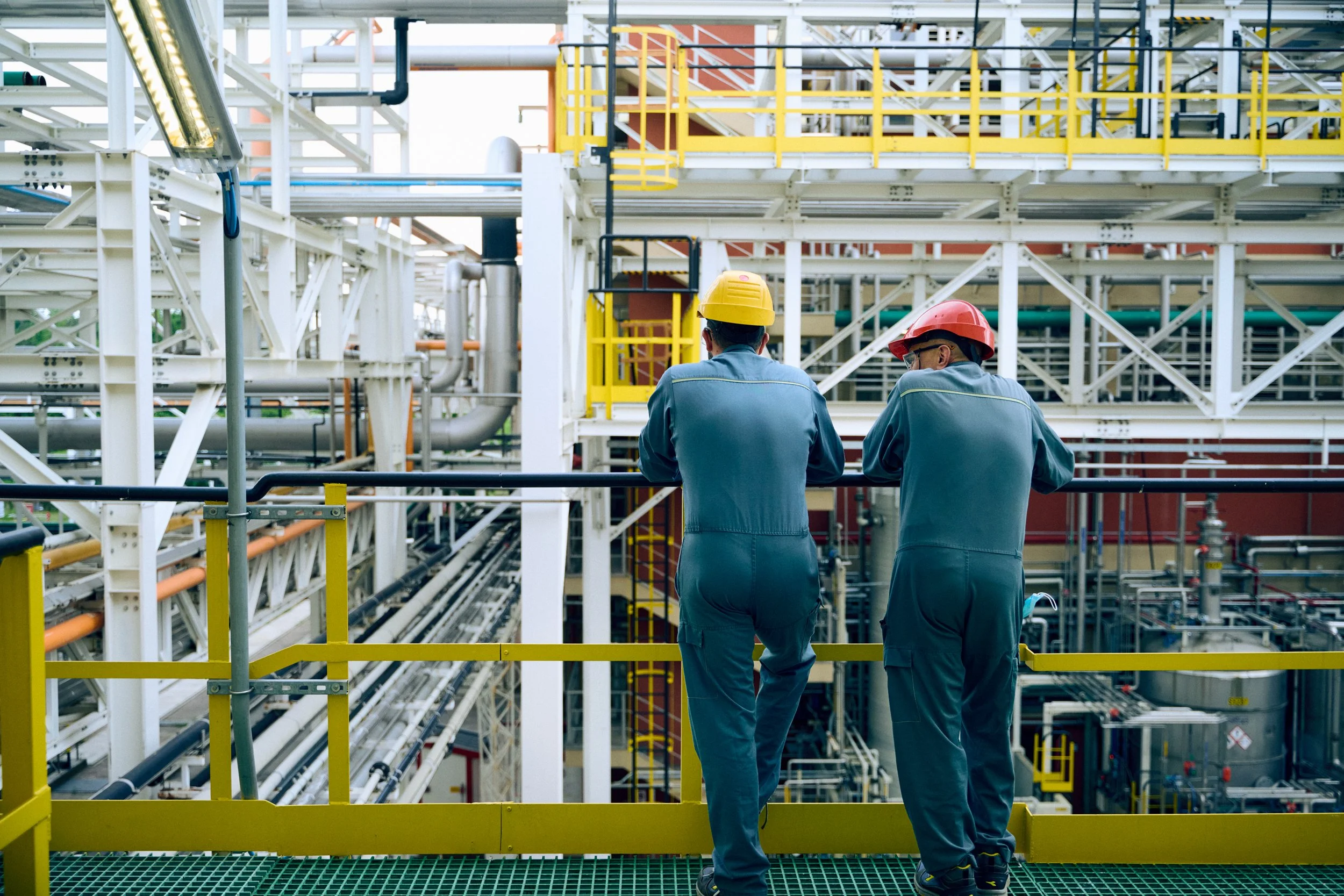 Two technicians observing production line from elevated platform within facility