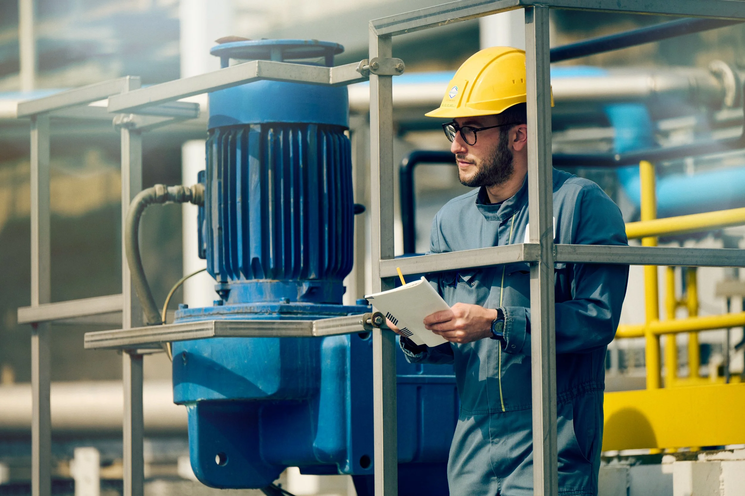 echnician inspecting pump installation while holding documentation, process verification