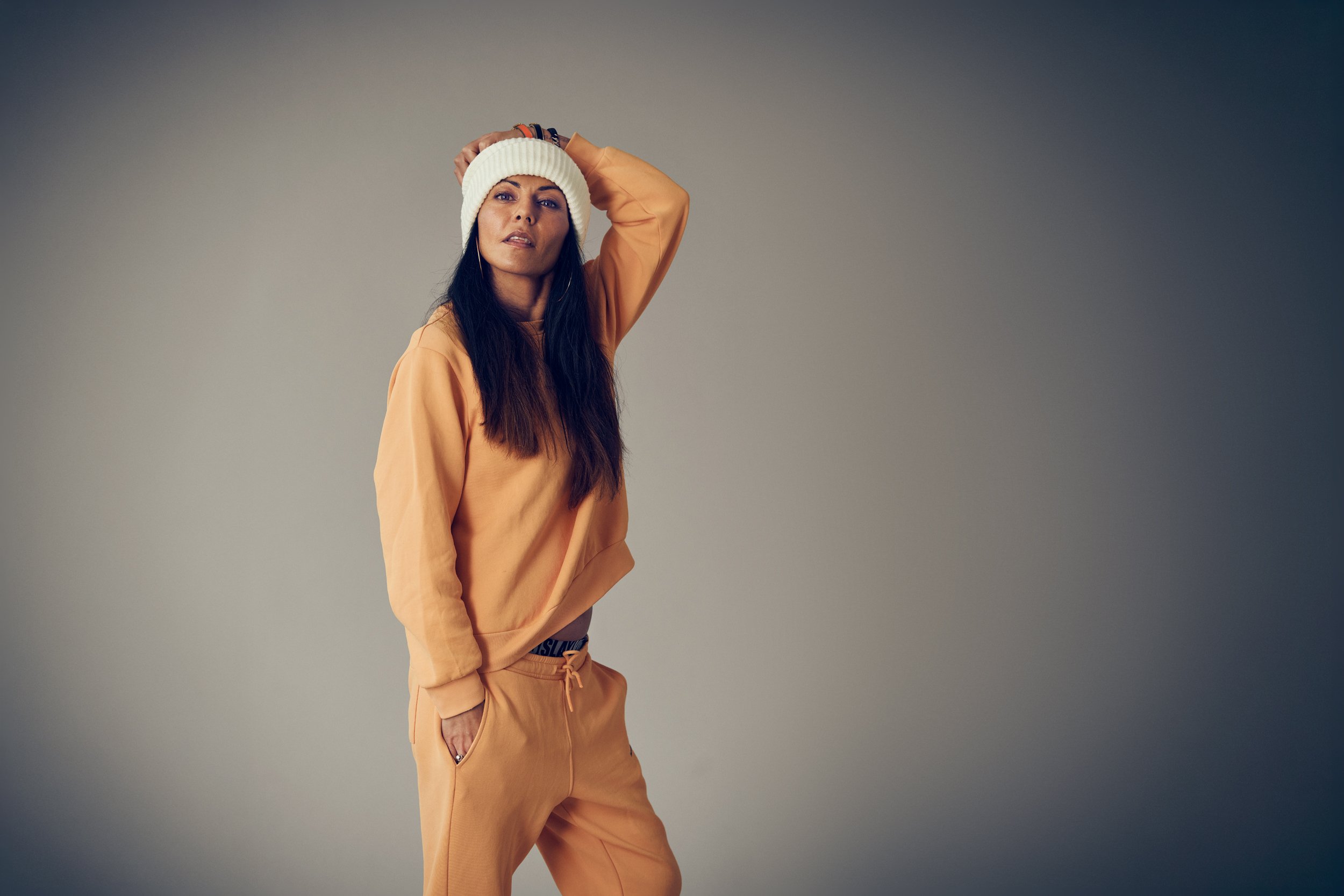 Portrait of woman in casual clothing standing against neutral background, confident posture