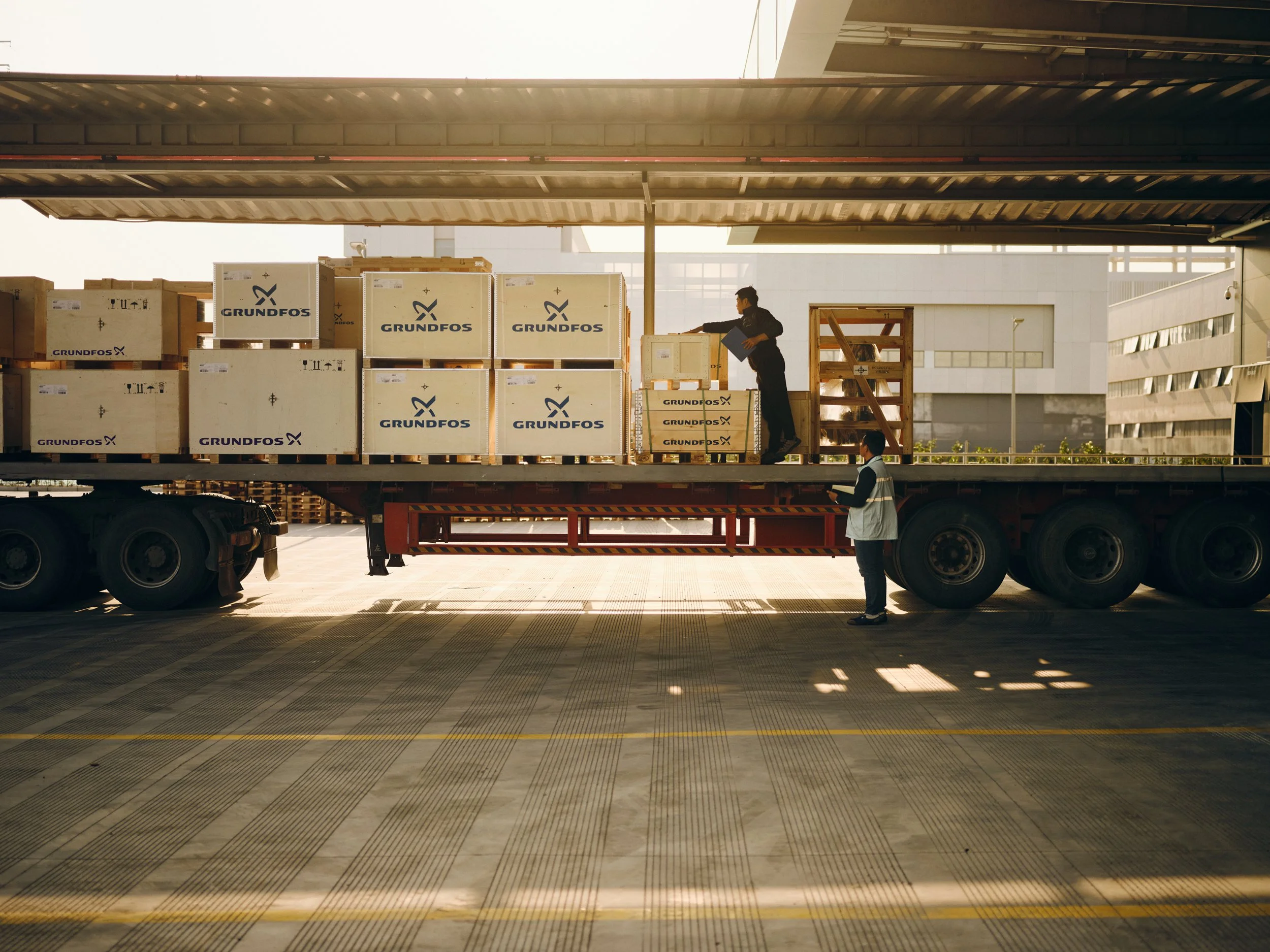 Workers loading Grundfos equipment onto truck at industrial loading dock