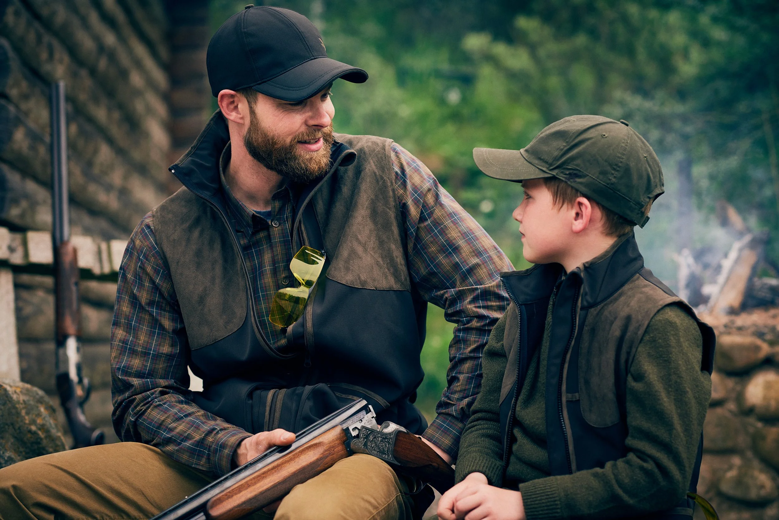Adult and child sitting together with shotgun, passing on knowledge in hunting setting