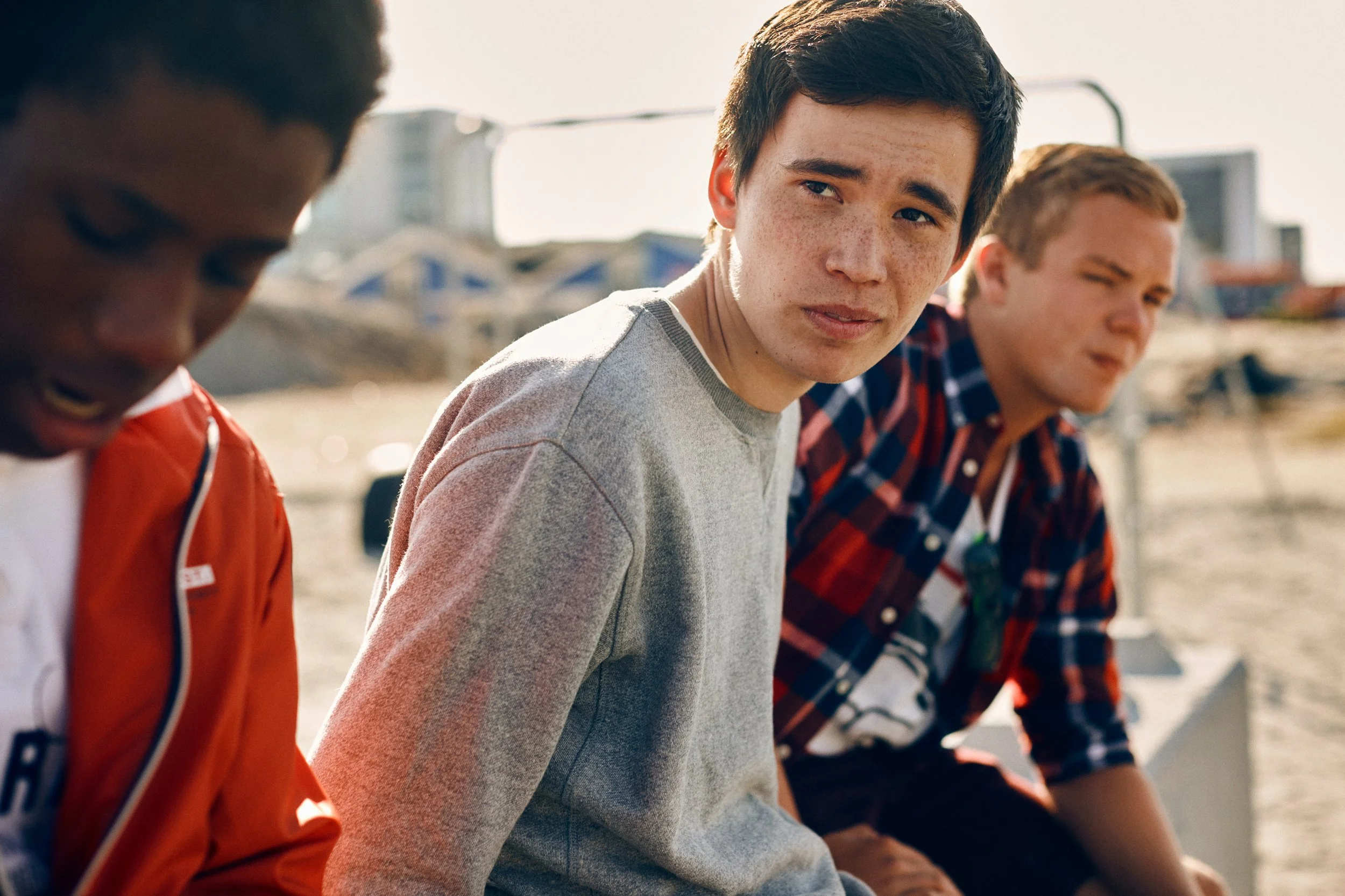 Three young men sitting together outdoors, casual conversation in urban setting