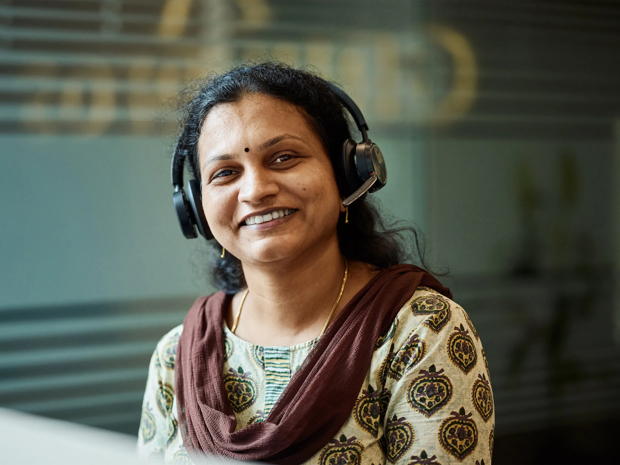 Customer service employee wearing headset smiling in office environment