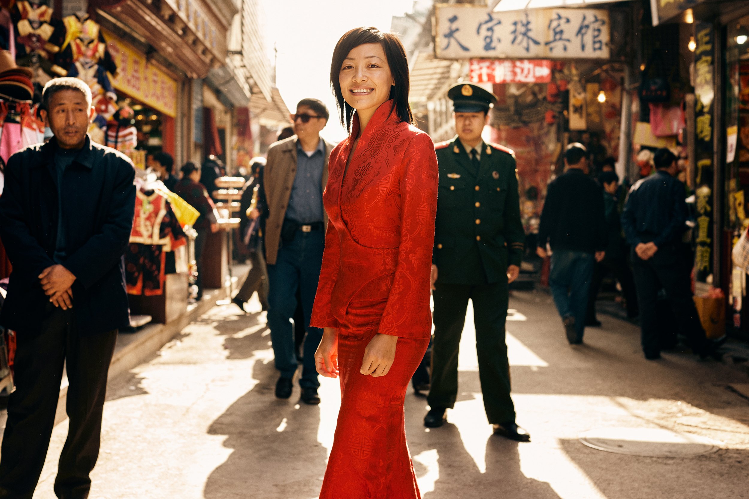 Woman in red dress walking through busy street market, cultural and social context of everyday life