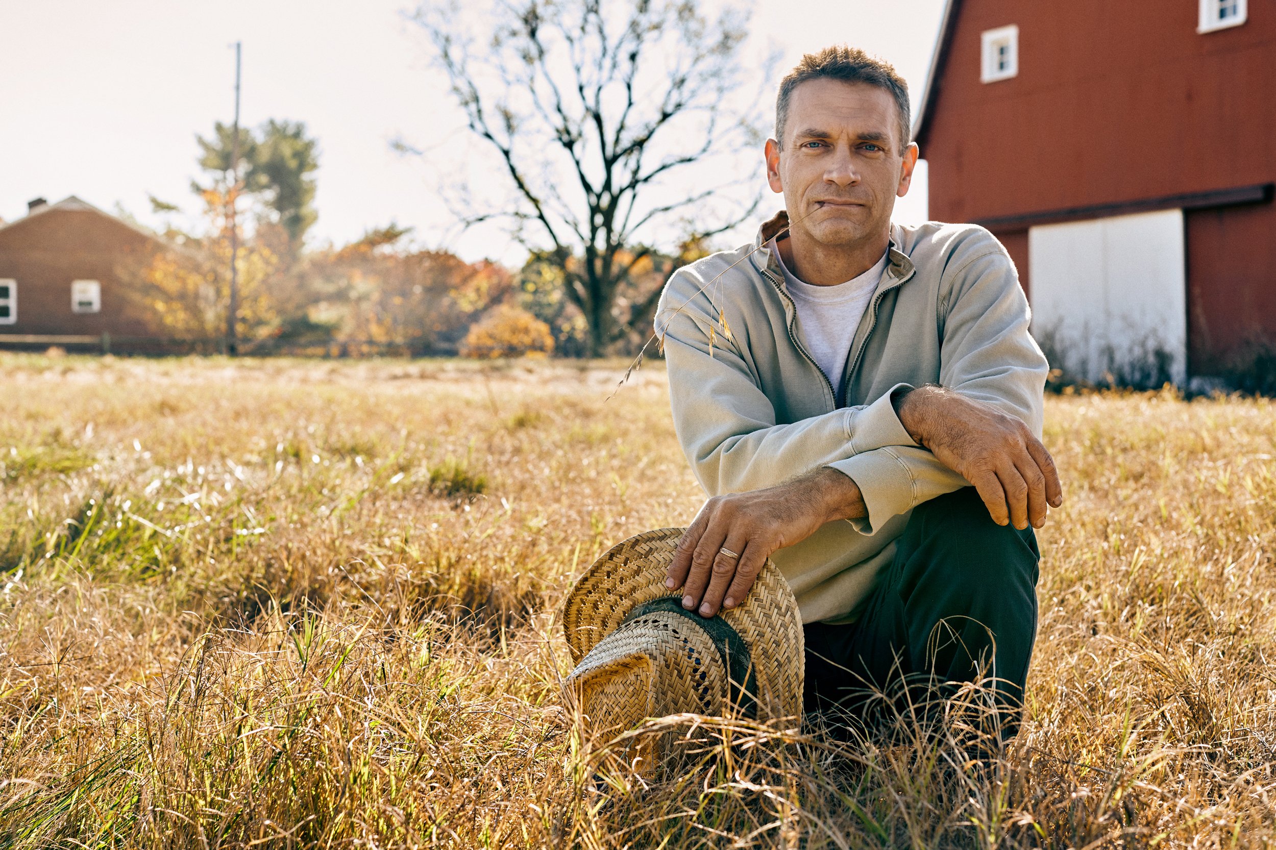 Farmer sitting in field near barn, agriculture context linked to biosolutions and crop production
