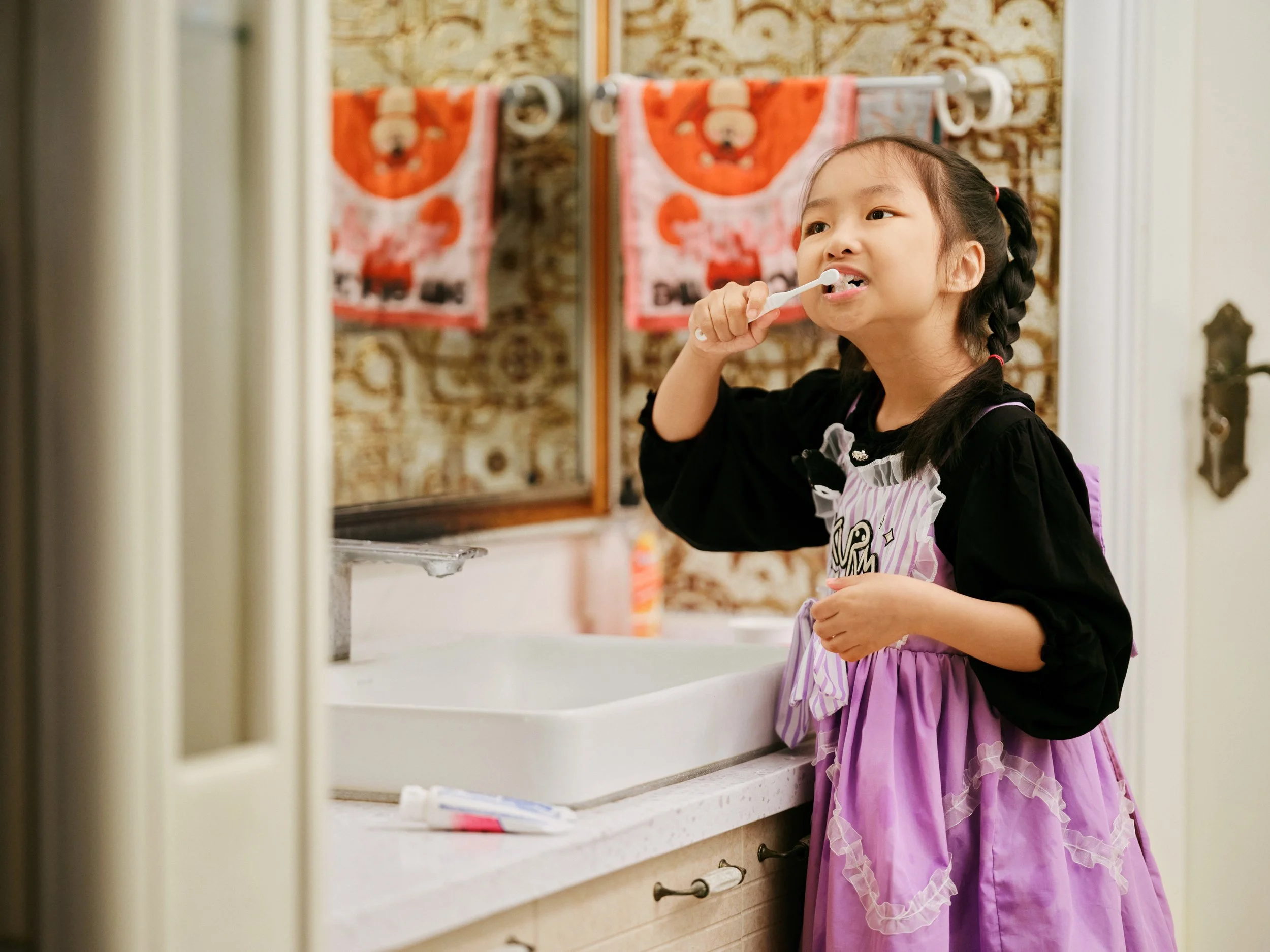 Child brushing teeth in bathroom at sink