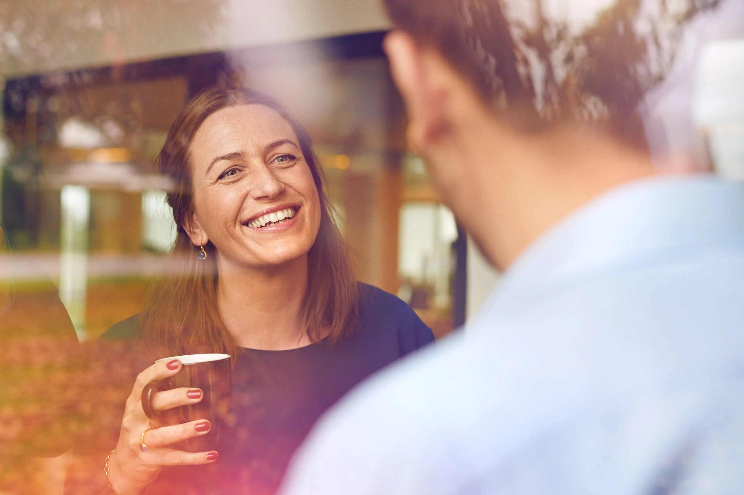 Two people talking over coffee indoors, relaxed social interaction