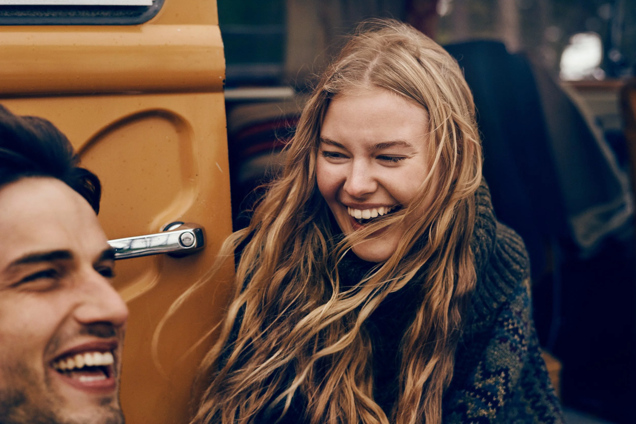 People sitting by van laughing together, social outdoor moment