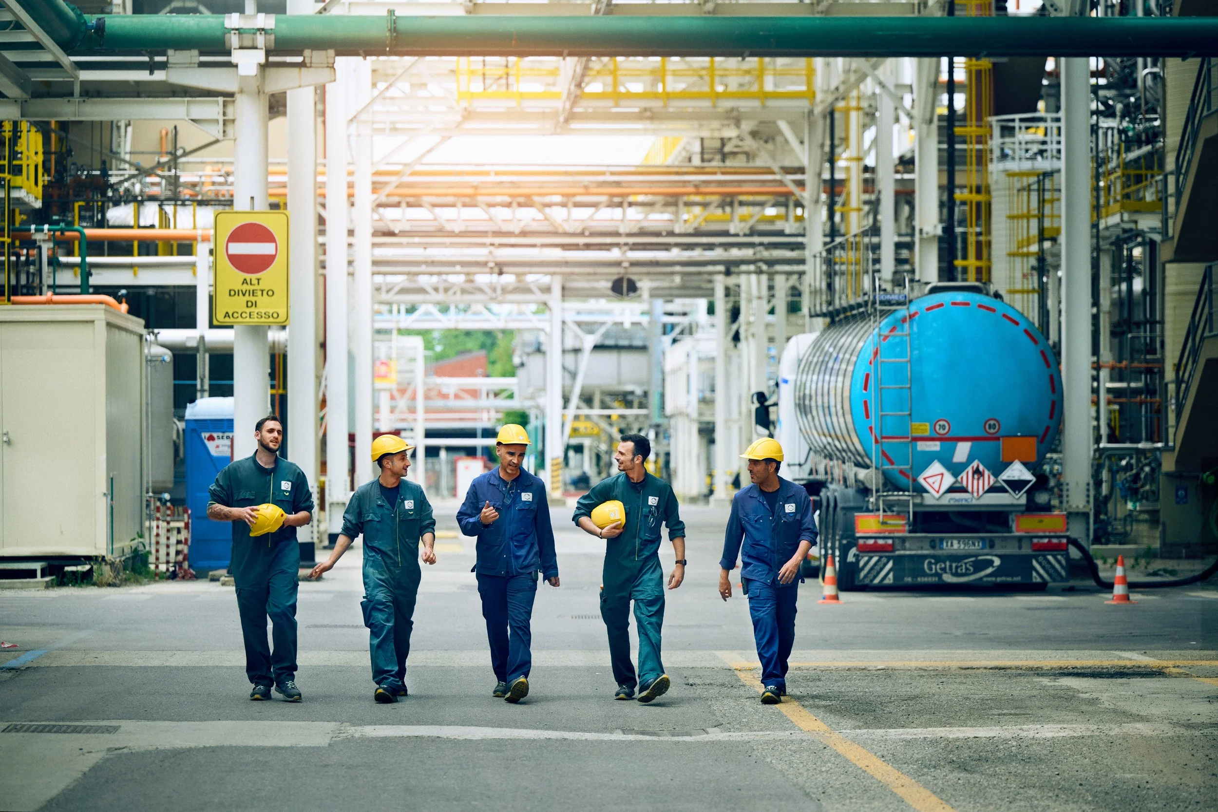 Group of workers walking through industrial facility, part of coordinated production environment