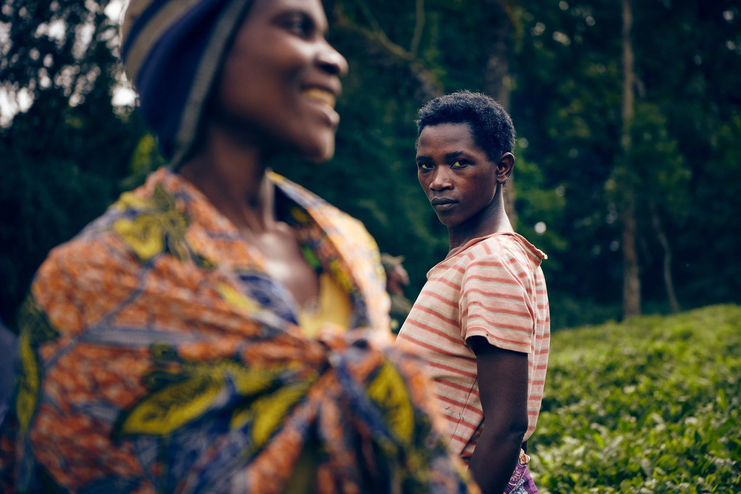 Woman in foreground smiling with another woman behind, layered social moment in field