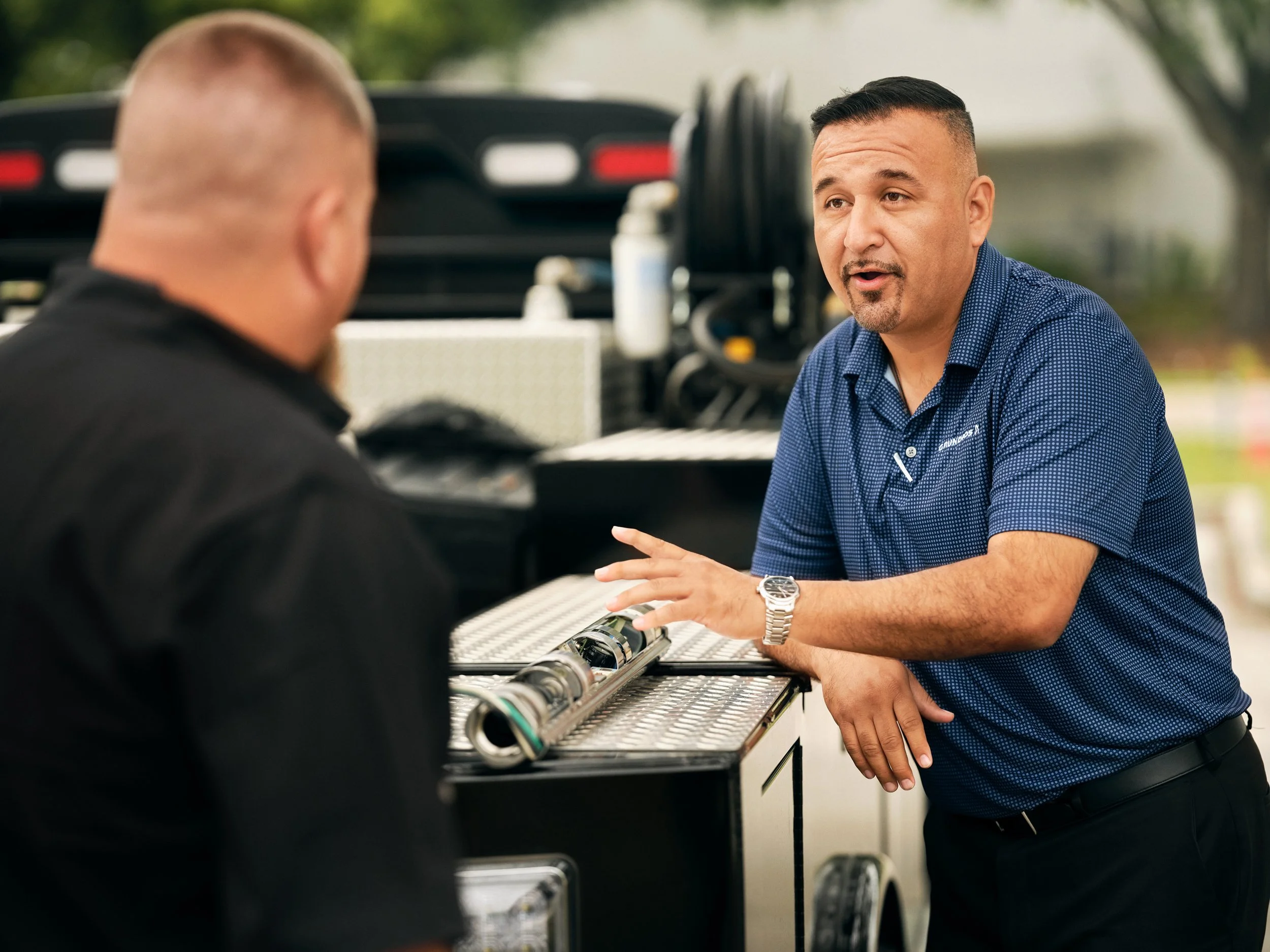 Two men talking beside service truck with pipe equipment