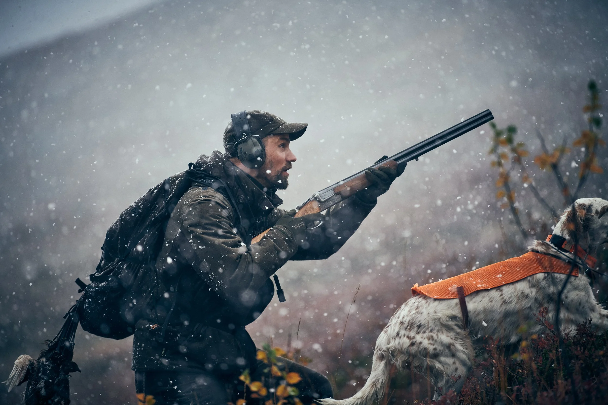 Hunter aiming rifle in snowy conditions, active hunting situation in harsh weather