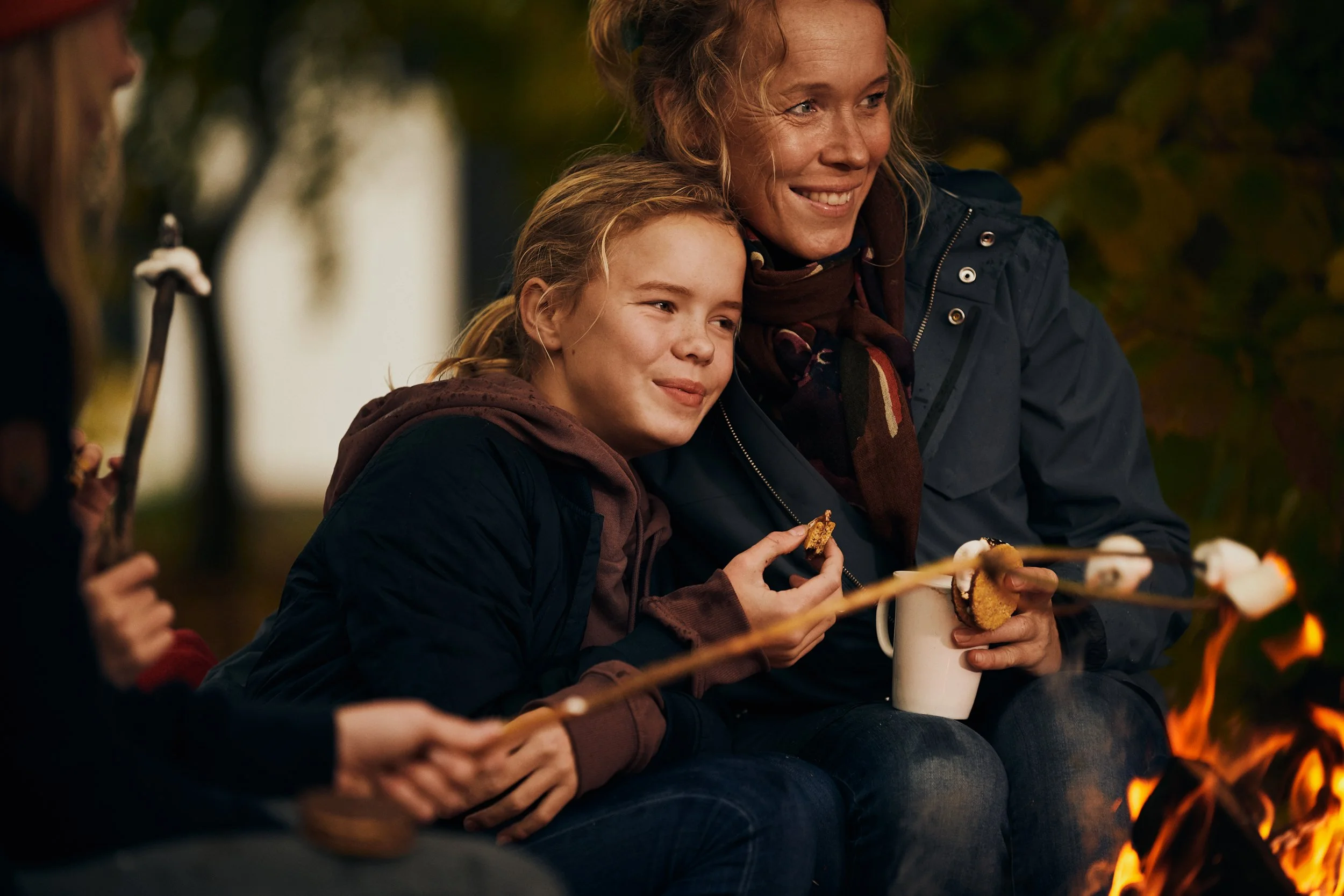 Girl roasting marshmallows by campfire, autumn outdoor moment