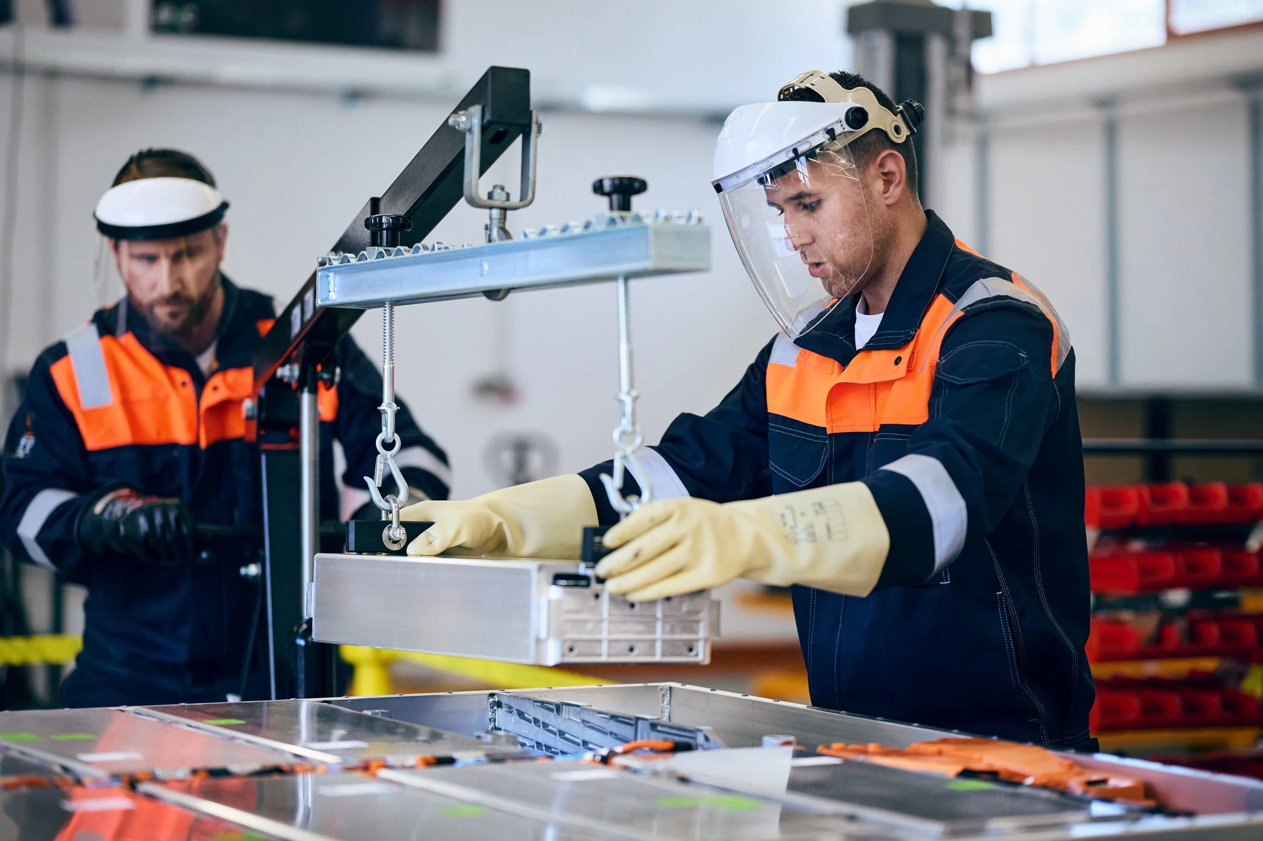 Technicians removing electric vehicle battery unit, controlled production process