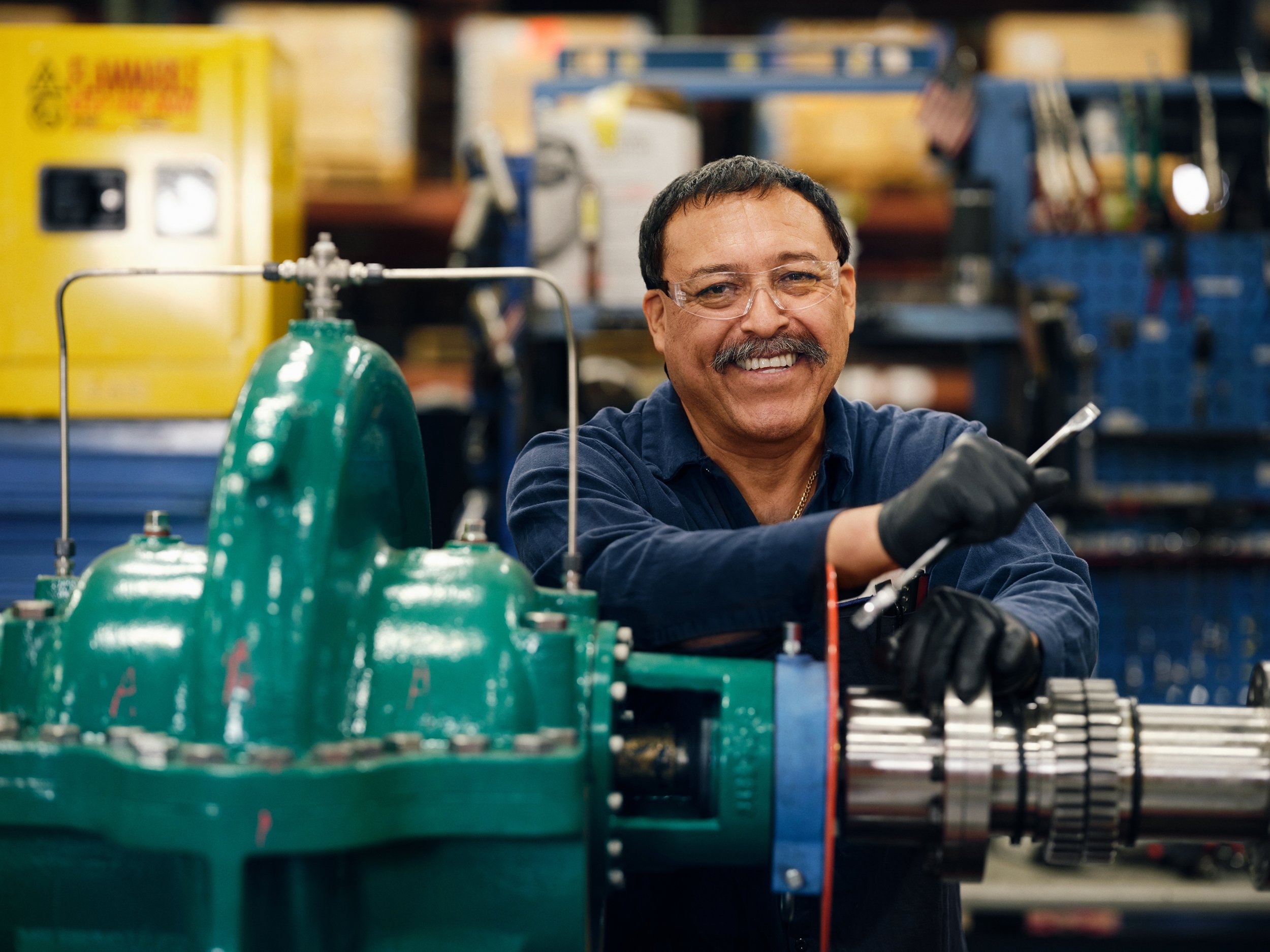 Technician working on green pump unit using tools in workshop environment