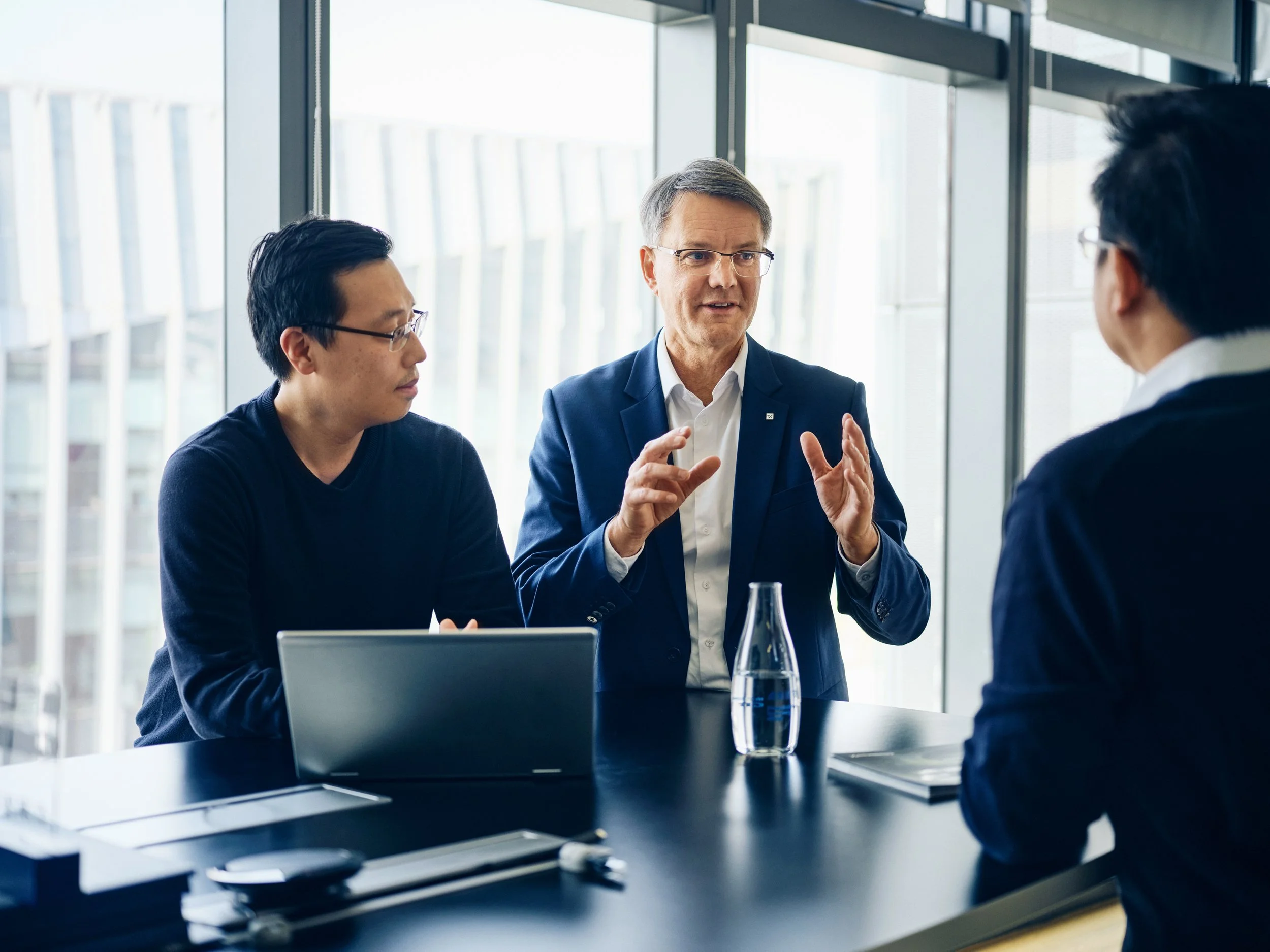 Executive speaking and gesturing during meeting with colleagues around table in modern office