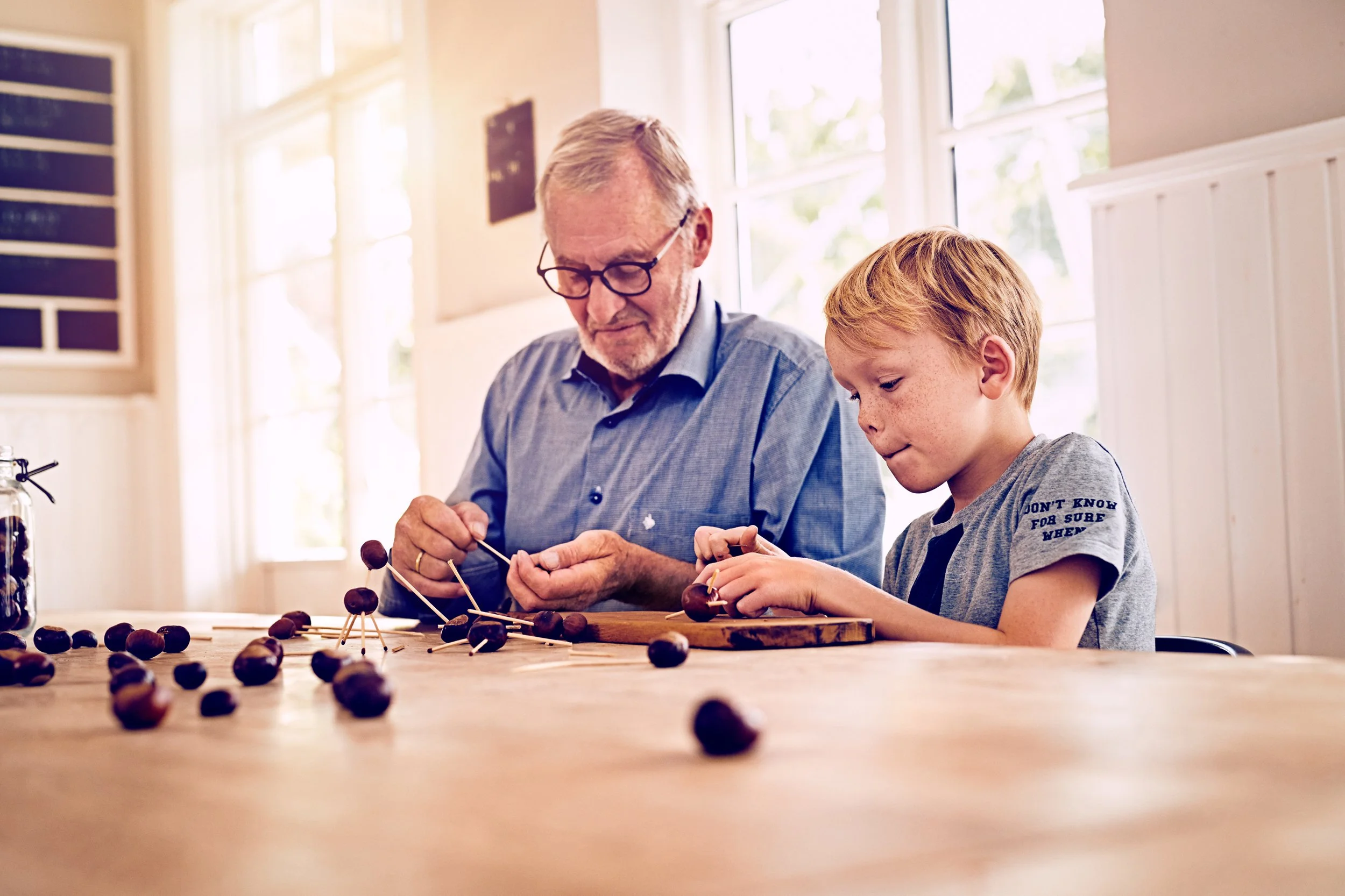 Adult and child making figures from chestnuts at table, shared creative activity indoors