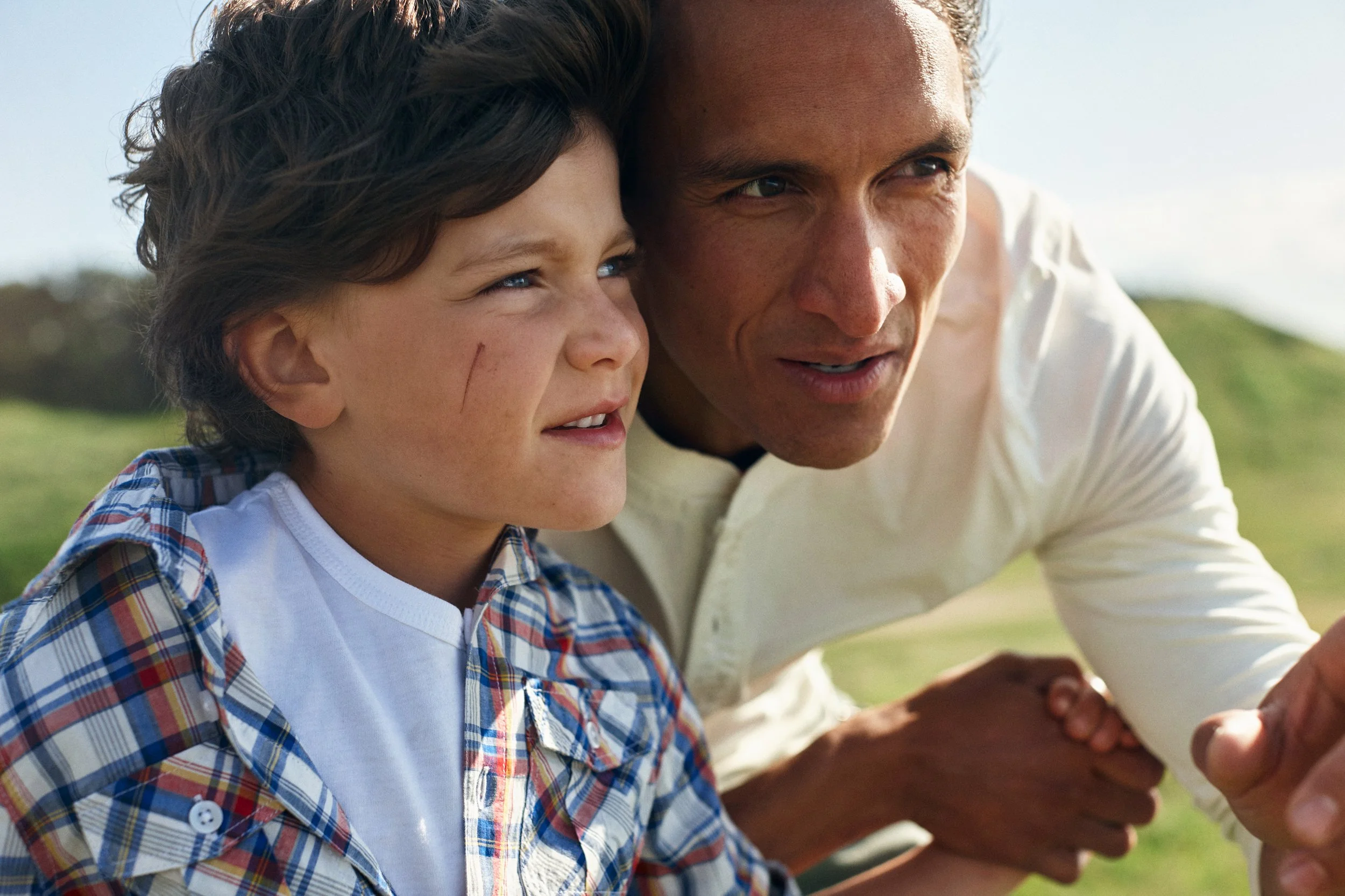 Adult and child looking into distance outdoors, close interaction in nature