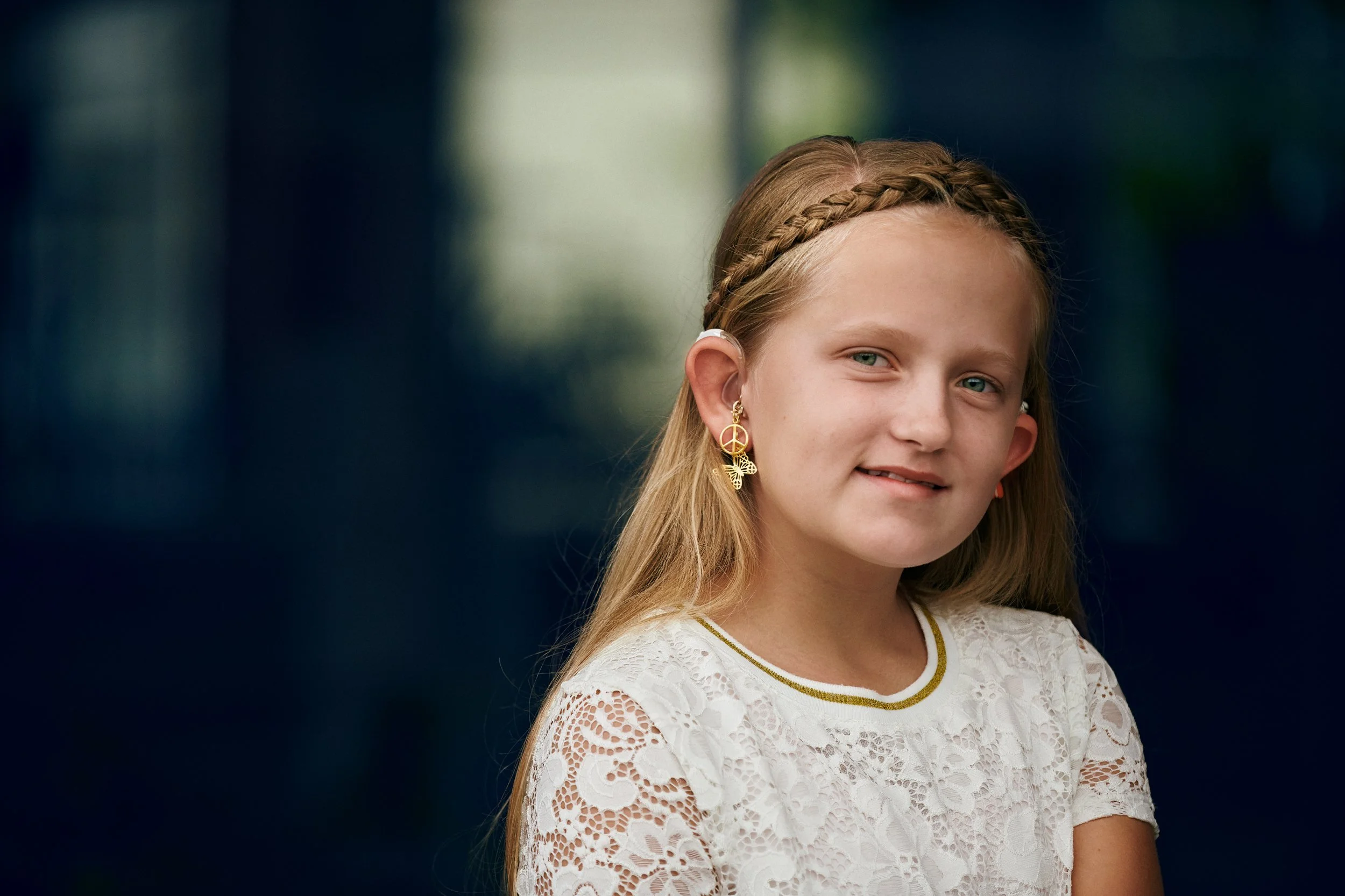 Portrait of girl wearing hearing aids, natural expression in outdoor setting