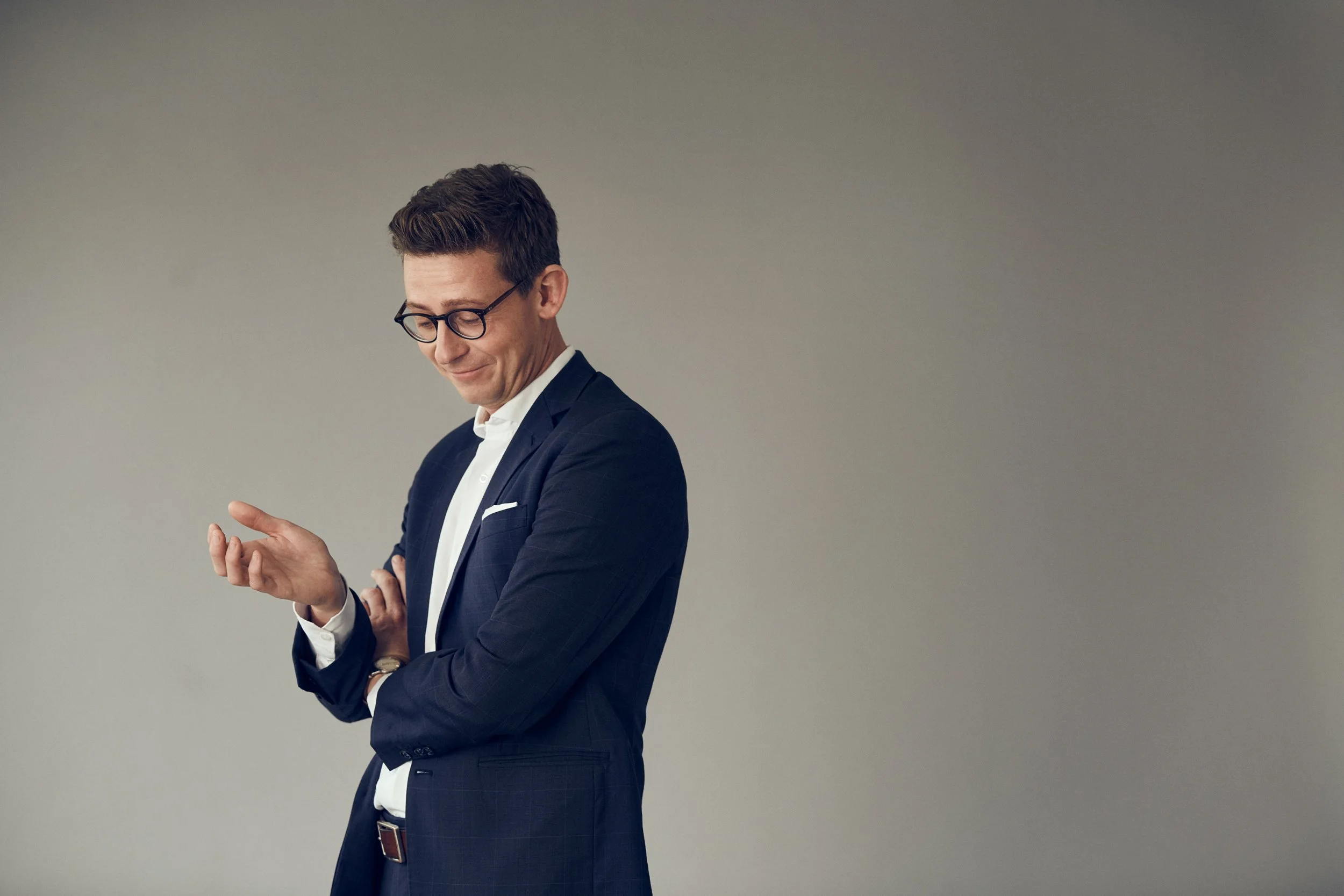 Portrait of man in suit looking down at hand, reflective moment