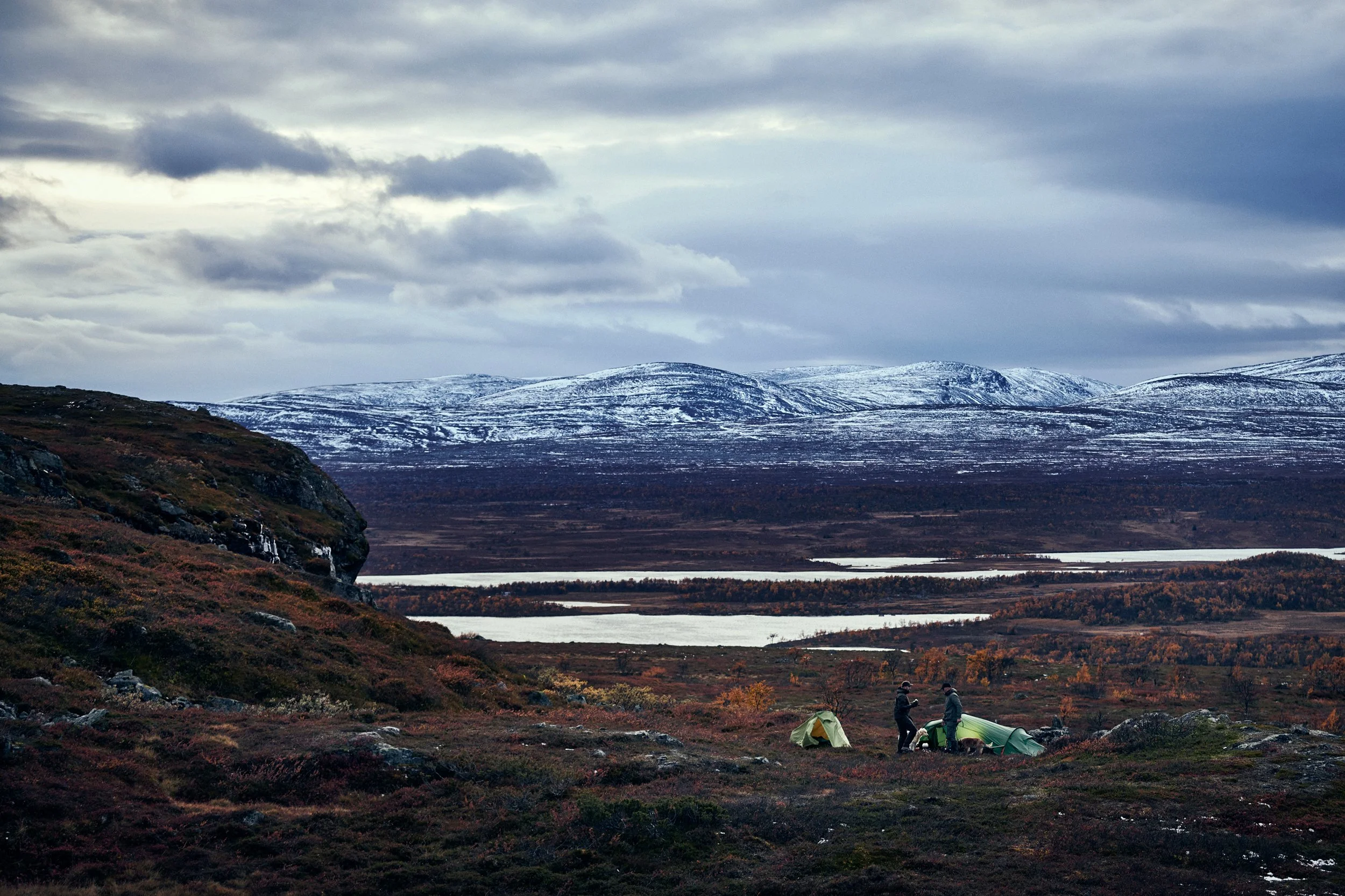 Wide landscape with hunters setting up tent in open arctic environment