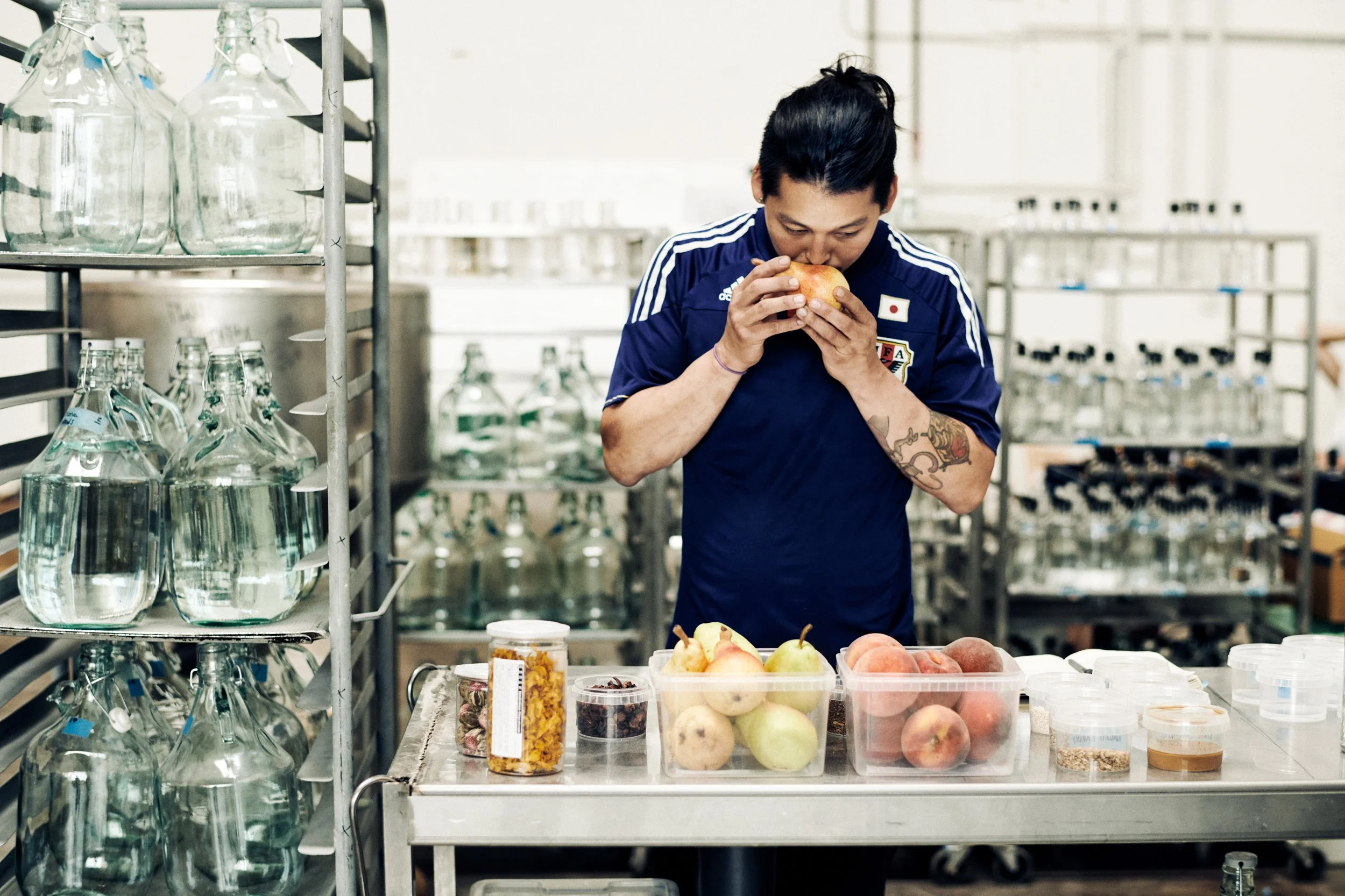 Worker smelling ingredients at table with bottles and produce, sensory evaluation