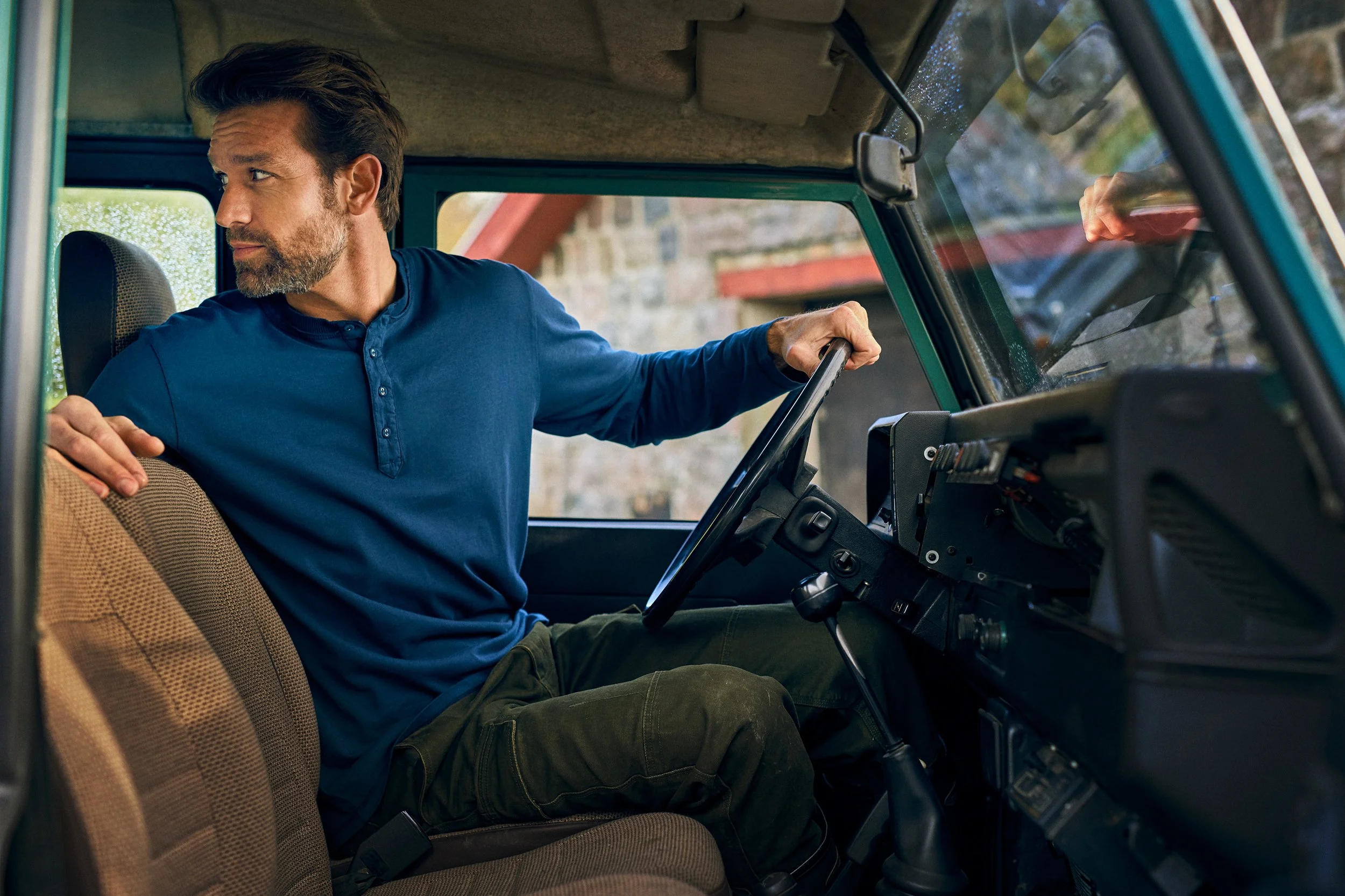 Man sitting in vehicle looking over shoulder, transition moment before driving