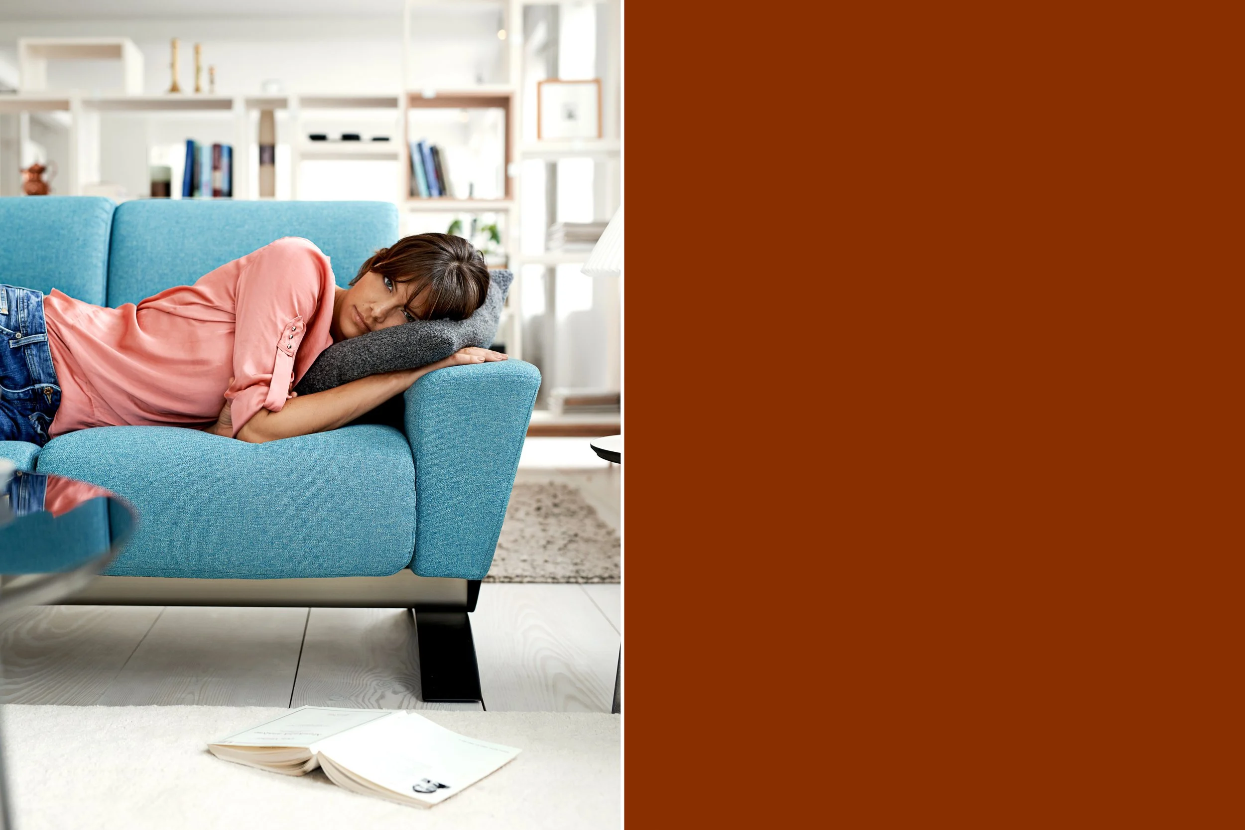 Woman lying on sofa with head on cushion, resting in home environment