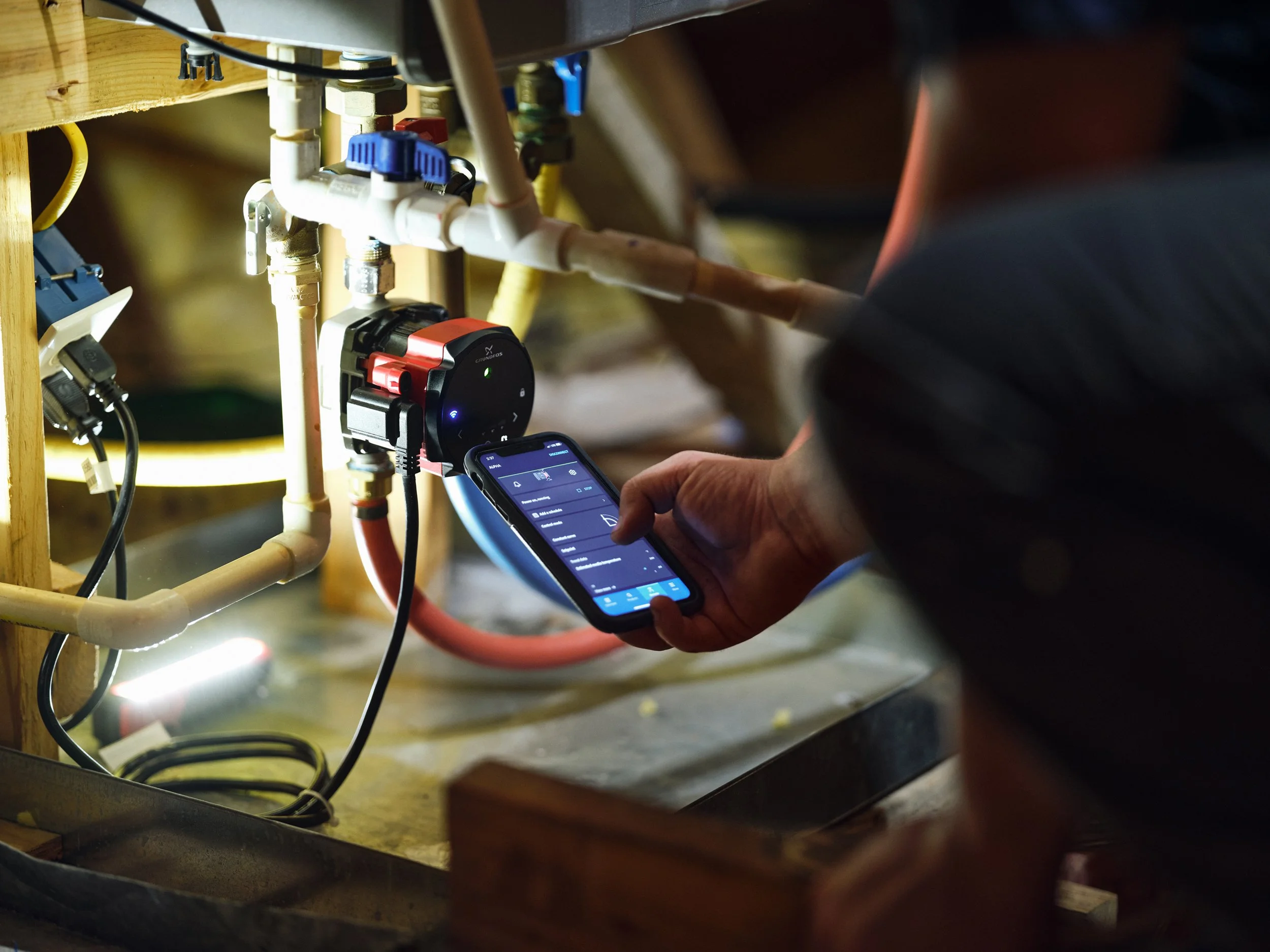 Smartphone controlling small pump installation with connected pipes