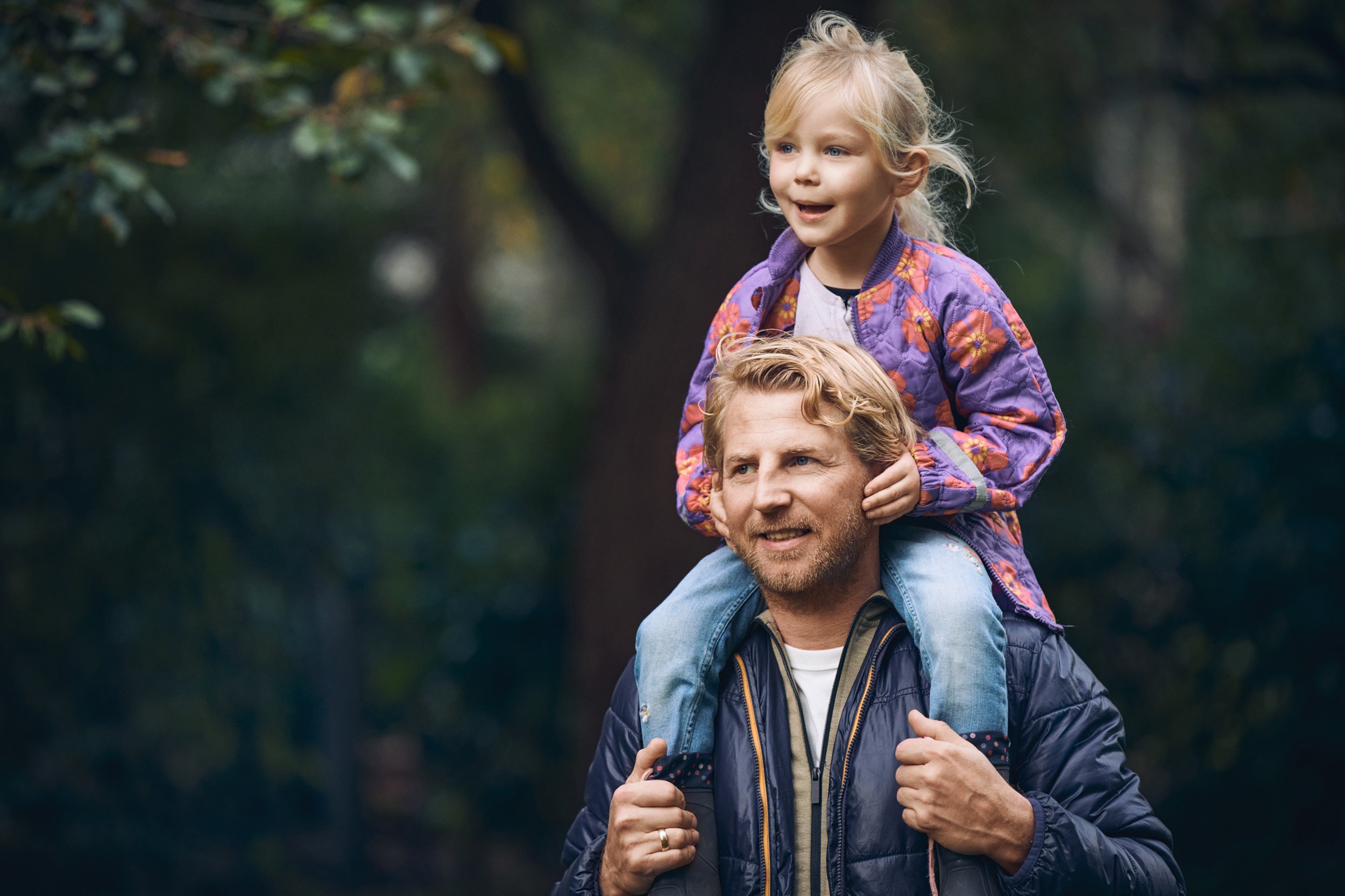Man carrying child on shoulders in park, close family moment outdoors