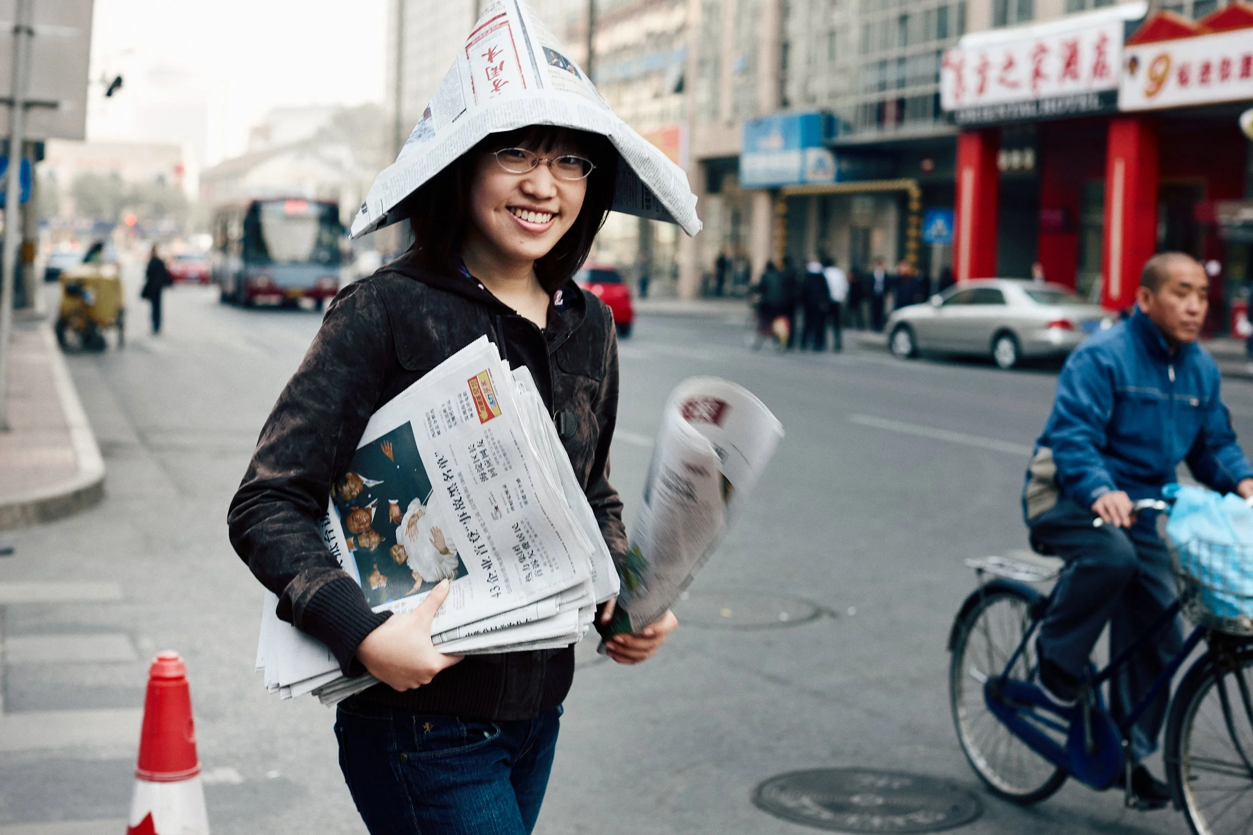 Young woman in urban street environment, She is wearing a hat made out of newpaper