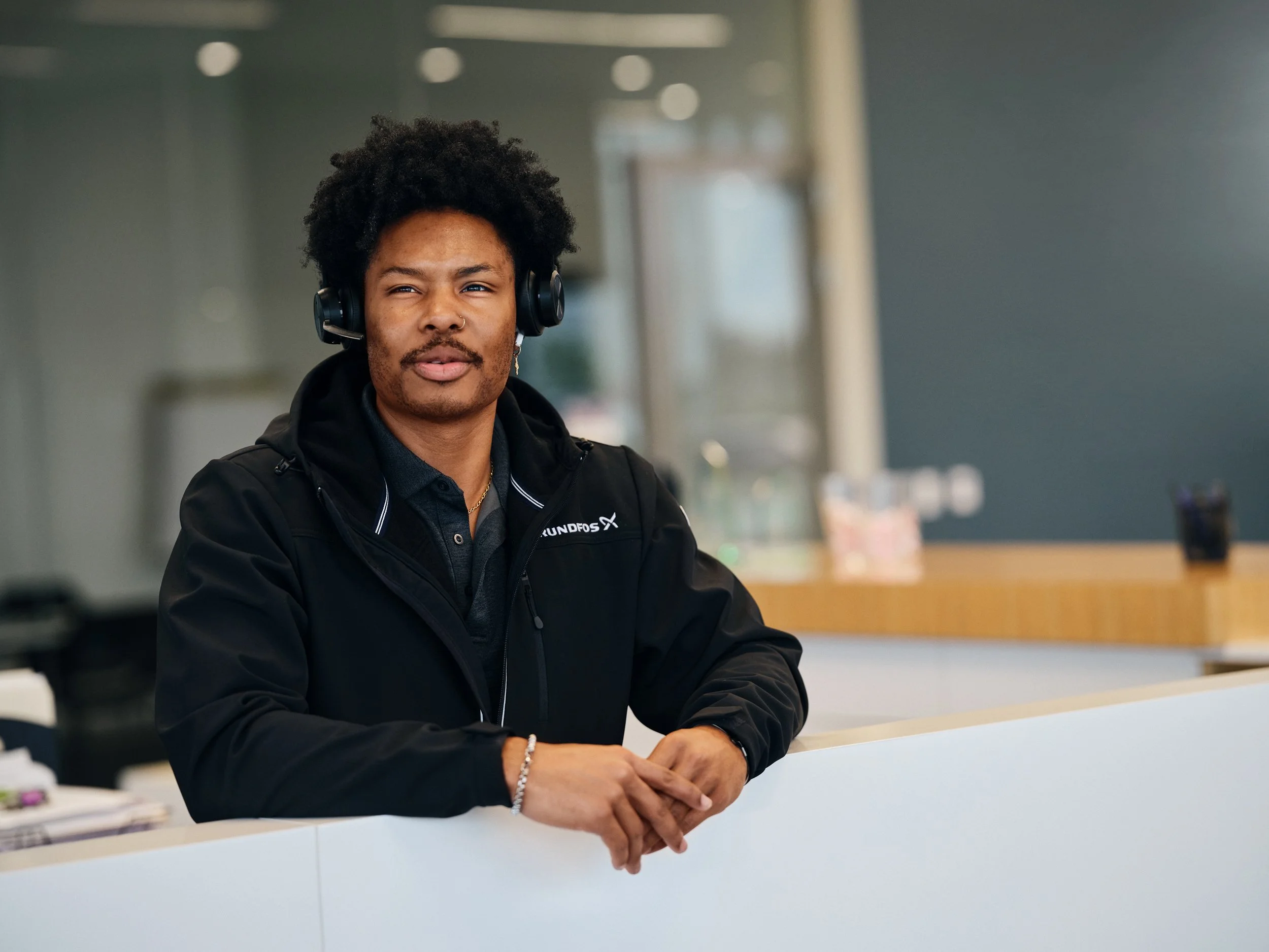 Front desk employee with headset in reception area, illustrating customer-facing service function